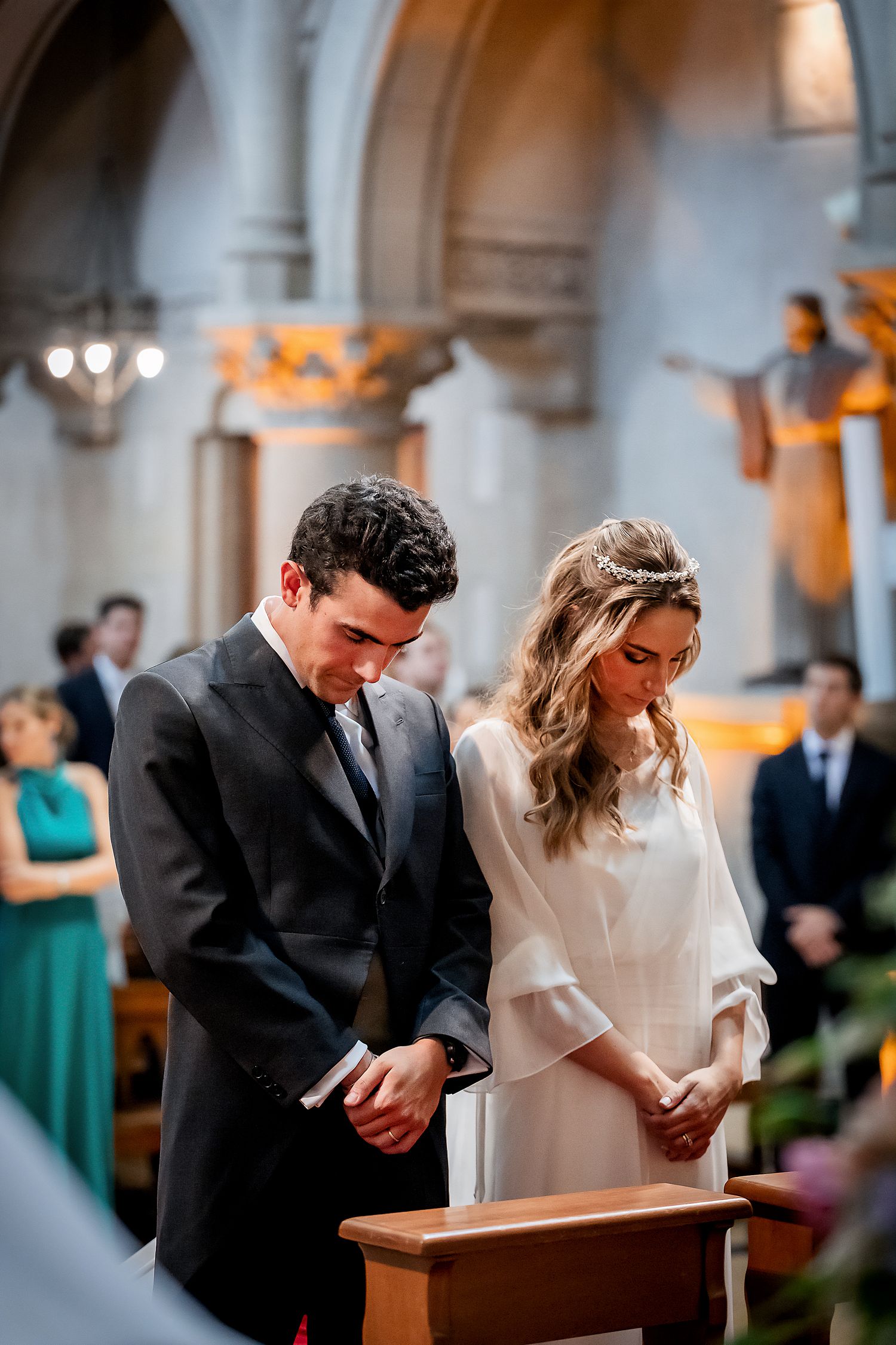 Bride and groom bow heads in prayer together at the altar during their wedding ceremony.