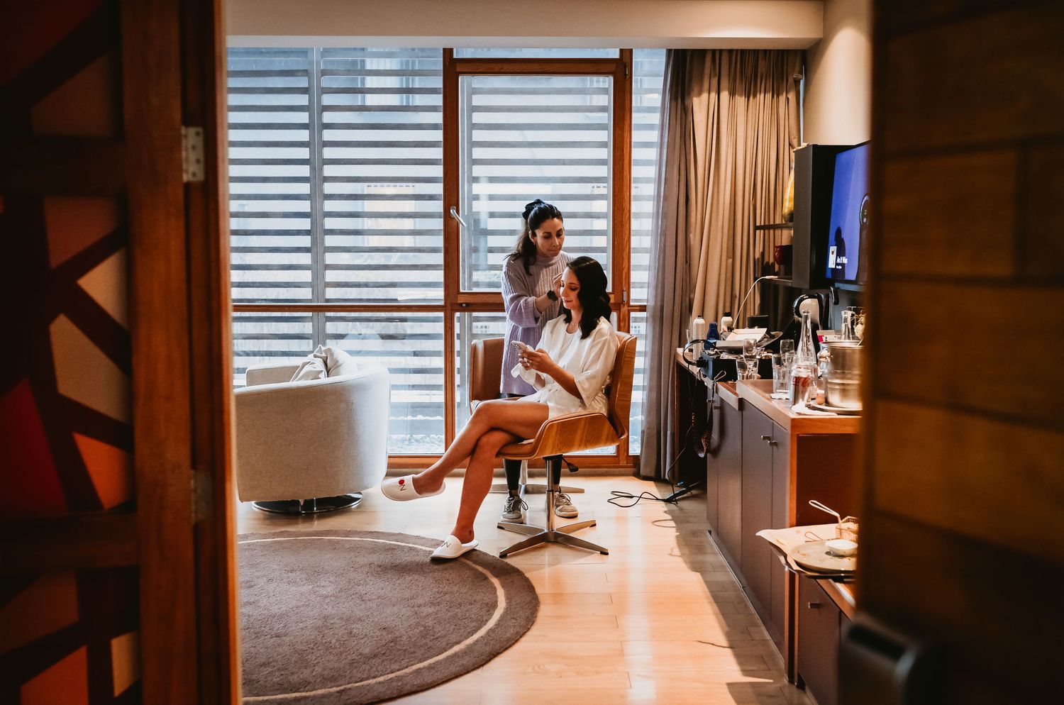 Two women relaxing in a modern hotel room with large windows and stylish decor.