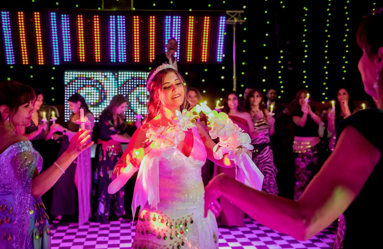 Bride in white gown dancing joyfully surrounded by guests at a vibrant wedding party.