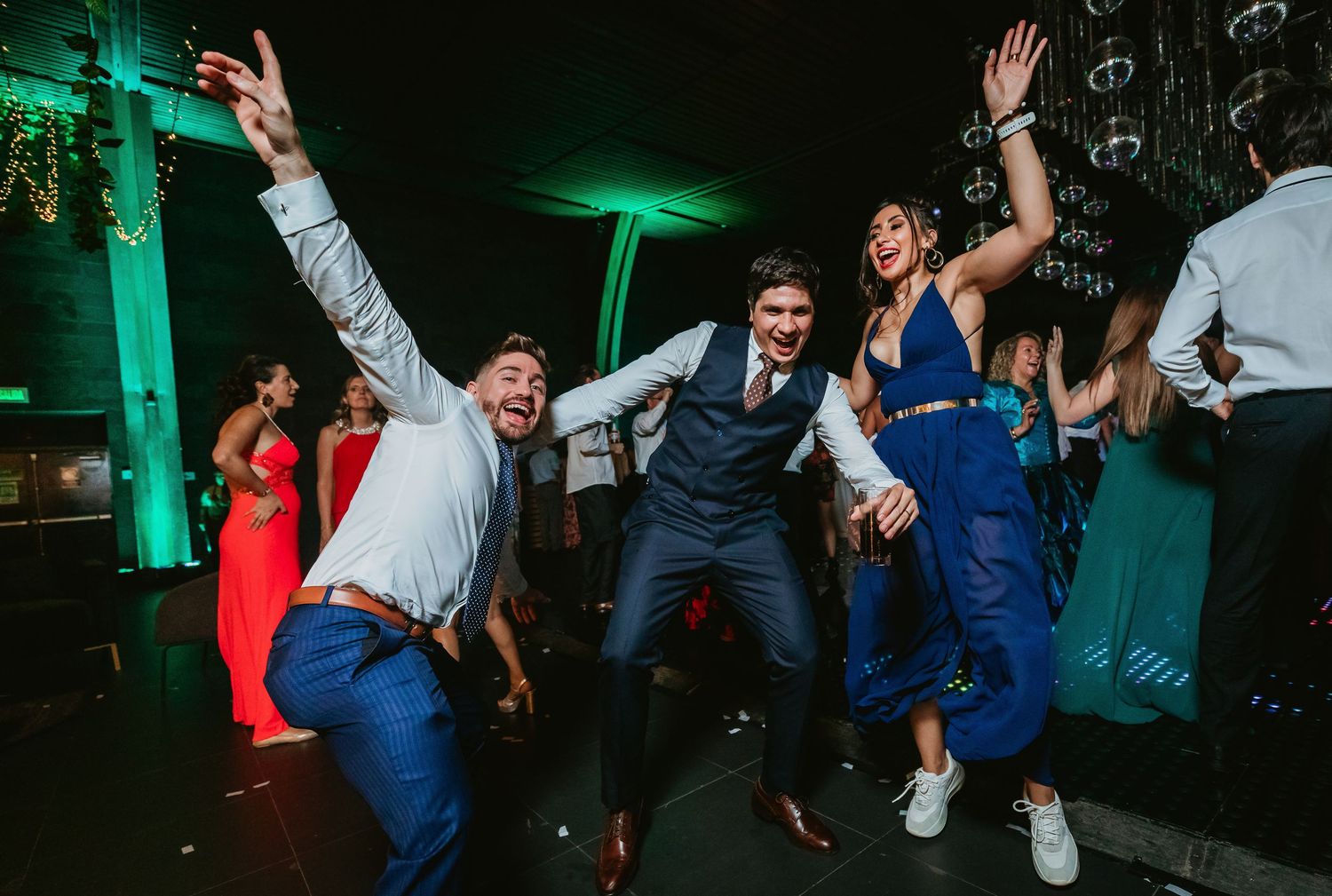 Groom and guests dance energetically on the dance floor at a festive wedding reception.