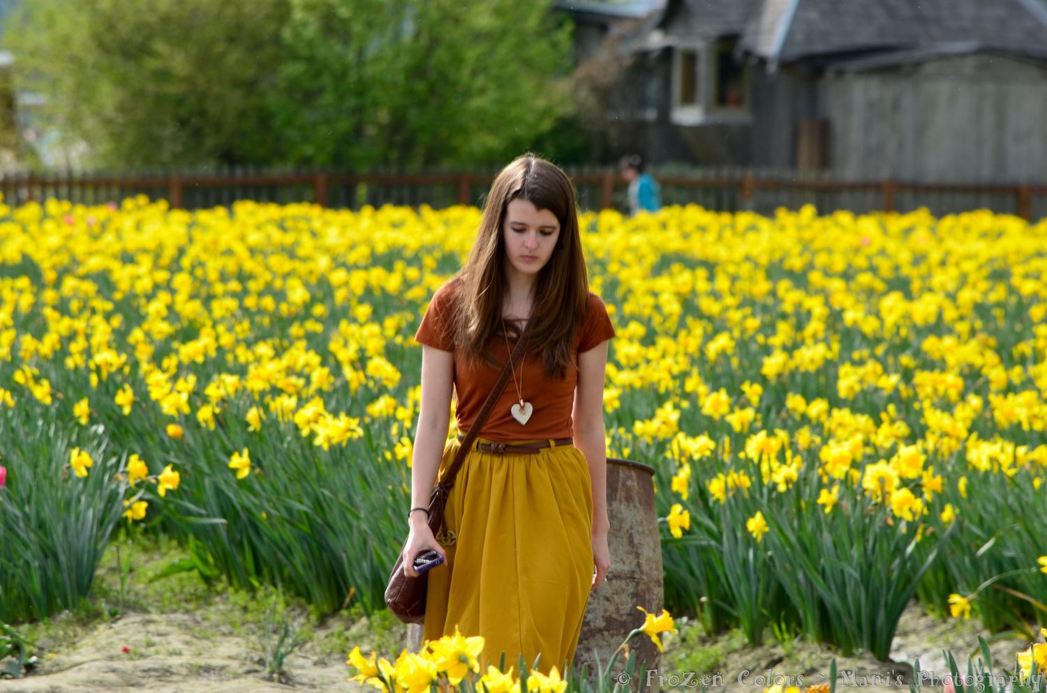 Young woman in mustard skirt standing in a vibrant yellow daffodil field during spring.
