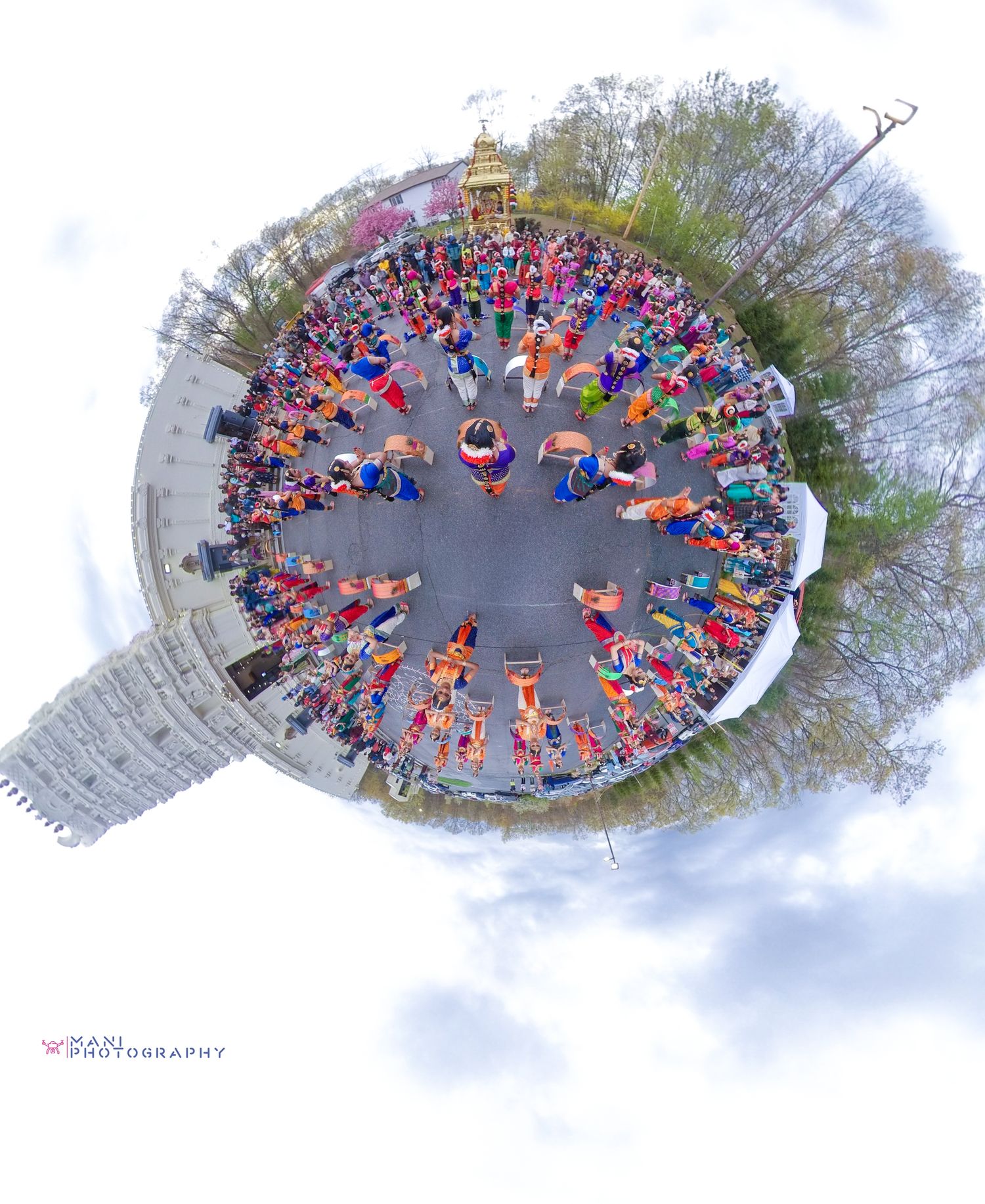 Aerial tiny planet photo of a colorful cultural festival with crowds of people in traditional attire gathered in a circular formation.