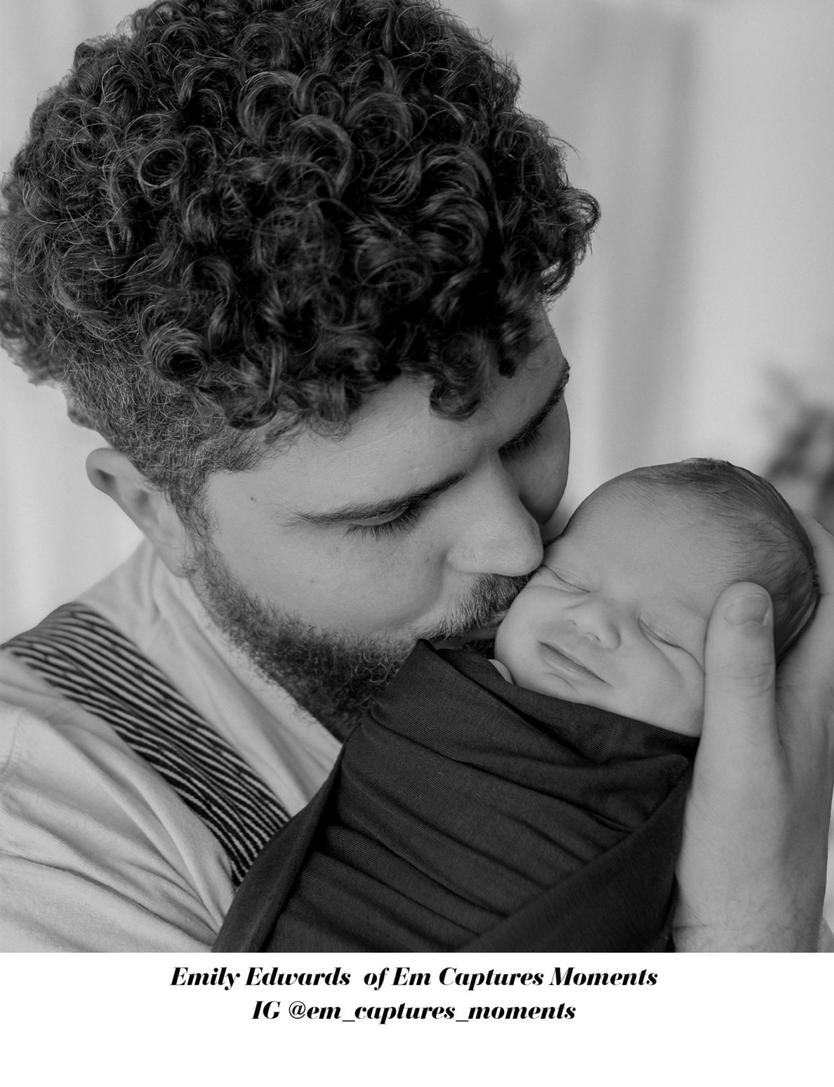 Black and white photo of curly-haired bearded father kissing sleeping swaddled newborn tenderly.