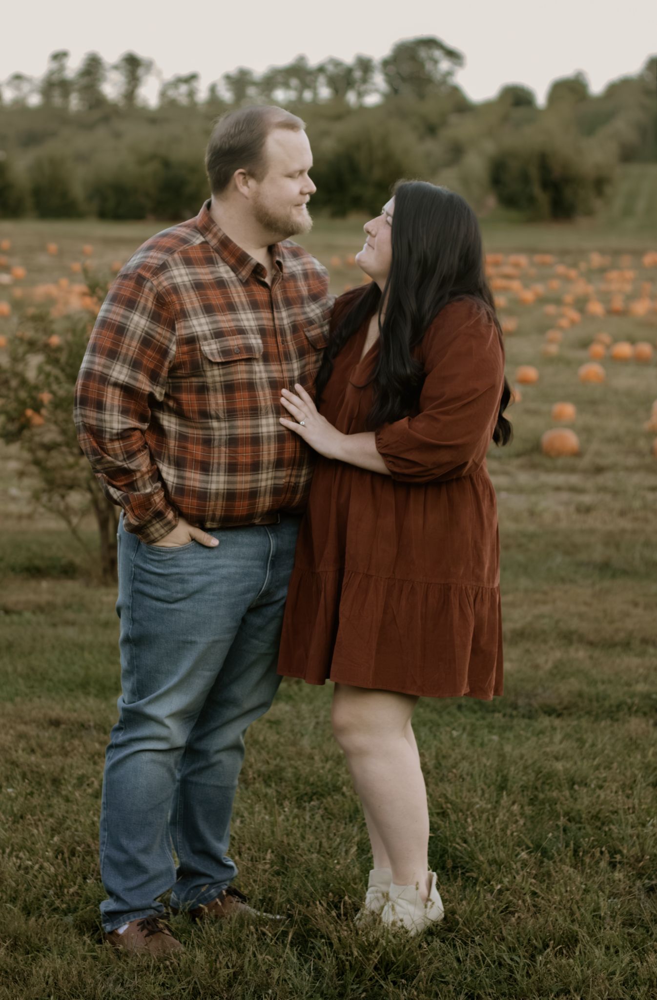 Loving couple sharing a tender moment together in a rustic fall pumpkin patch setting.