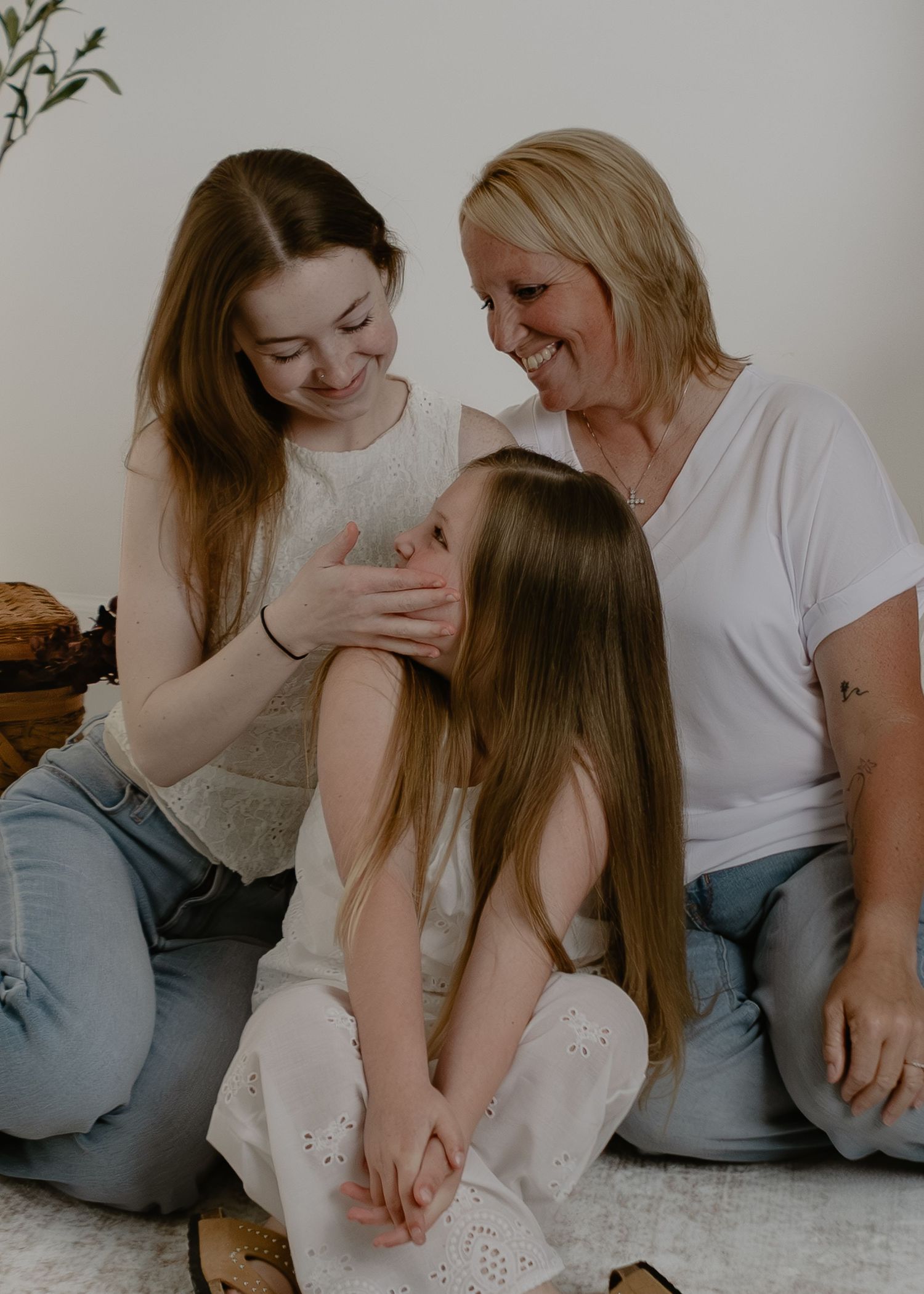 Mother and two daughters sharing a warm laugh together during an indoor family portrait session.