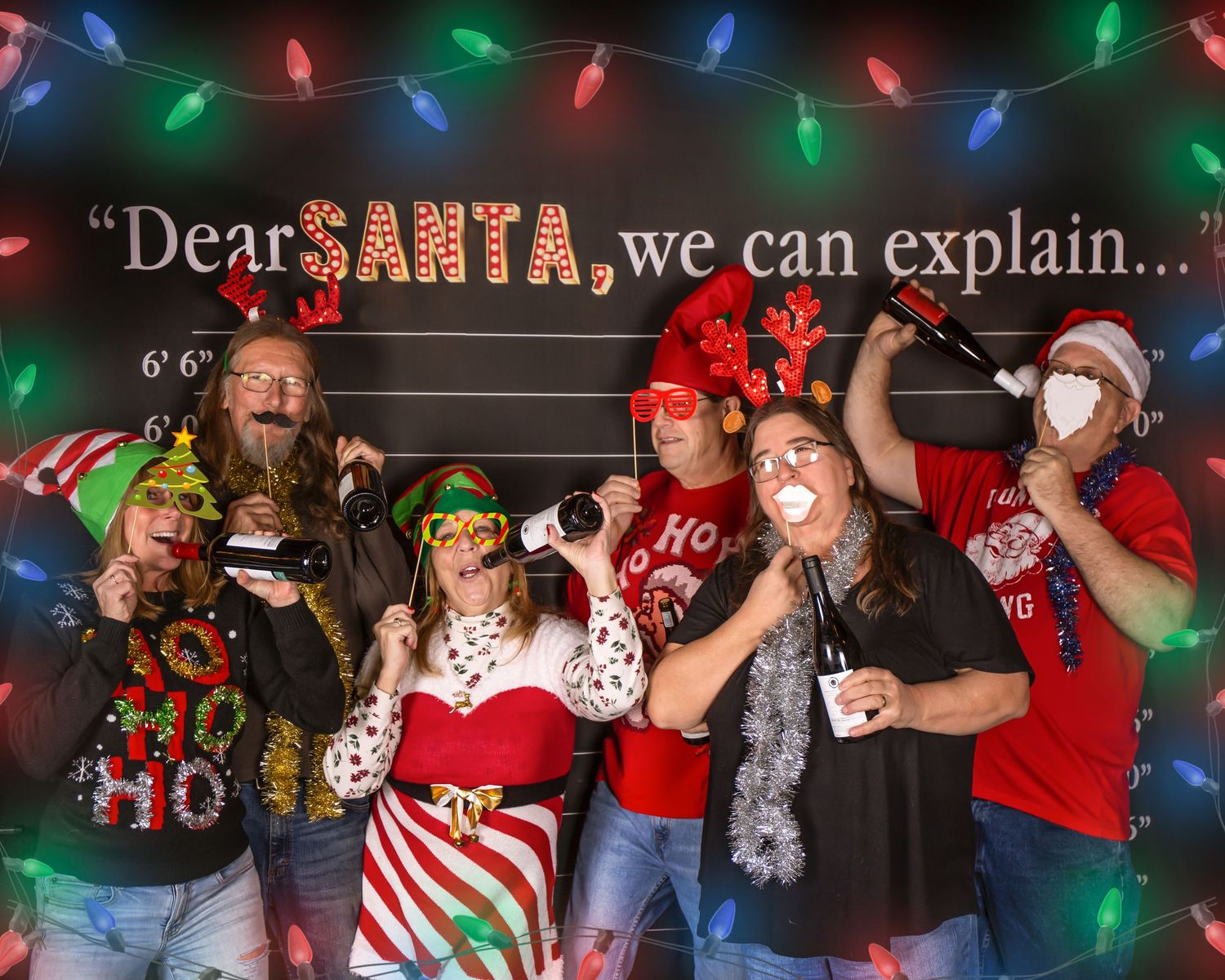 A festive group wearing holiday attire dances and celebrates at a Christmas party with colorful lights in the background.
