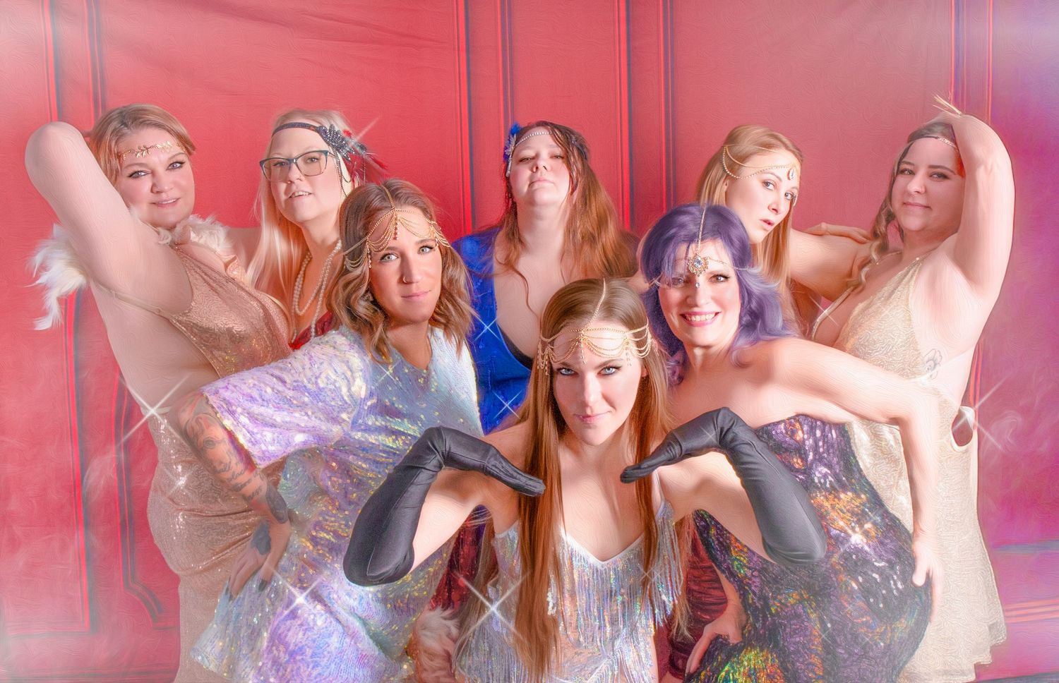 Group of dancers in sparkly costumes pose together against a red background with artistic blurred motion effect.