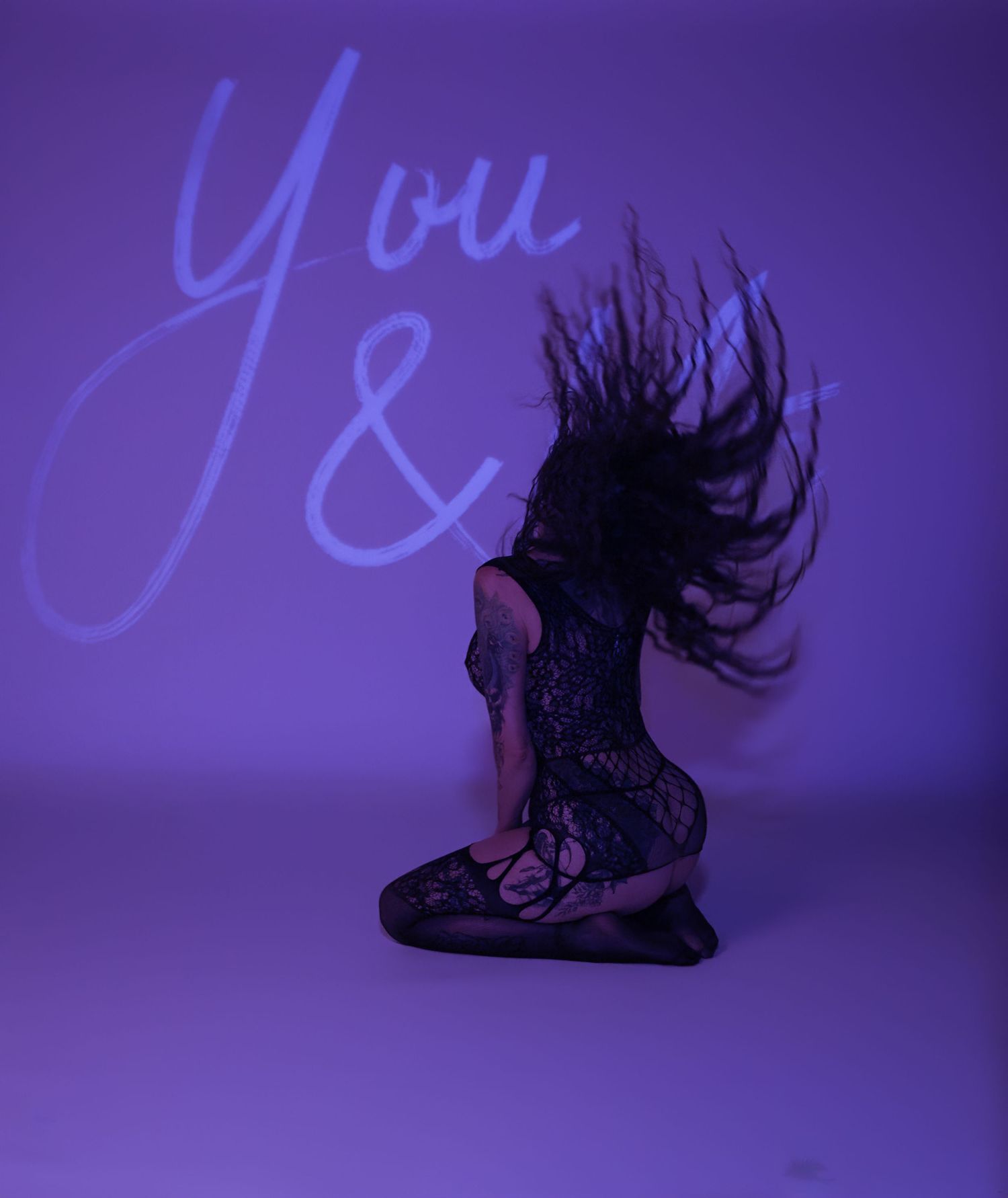 A silhouette of hair flowing dramatically against a purple and blue illuminated background.