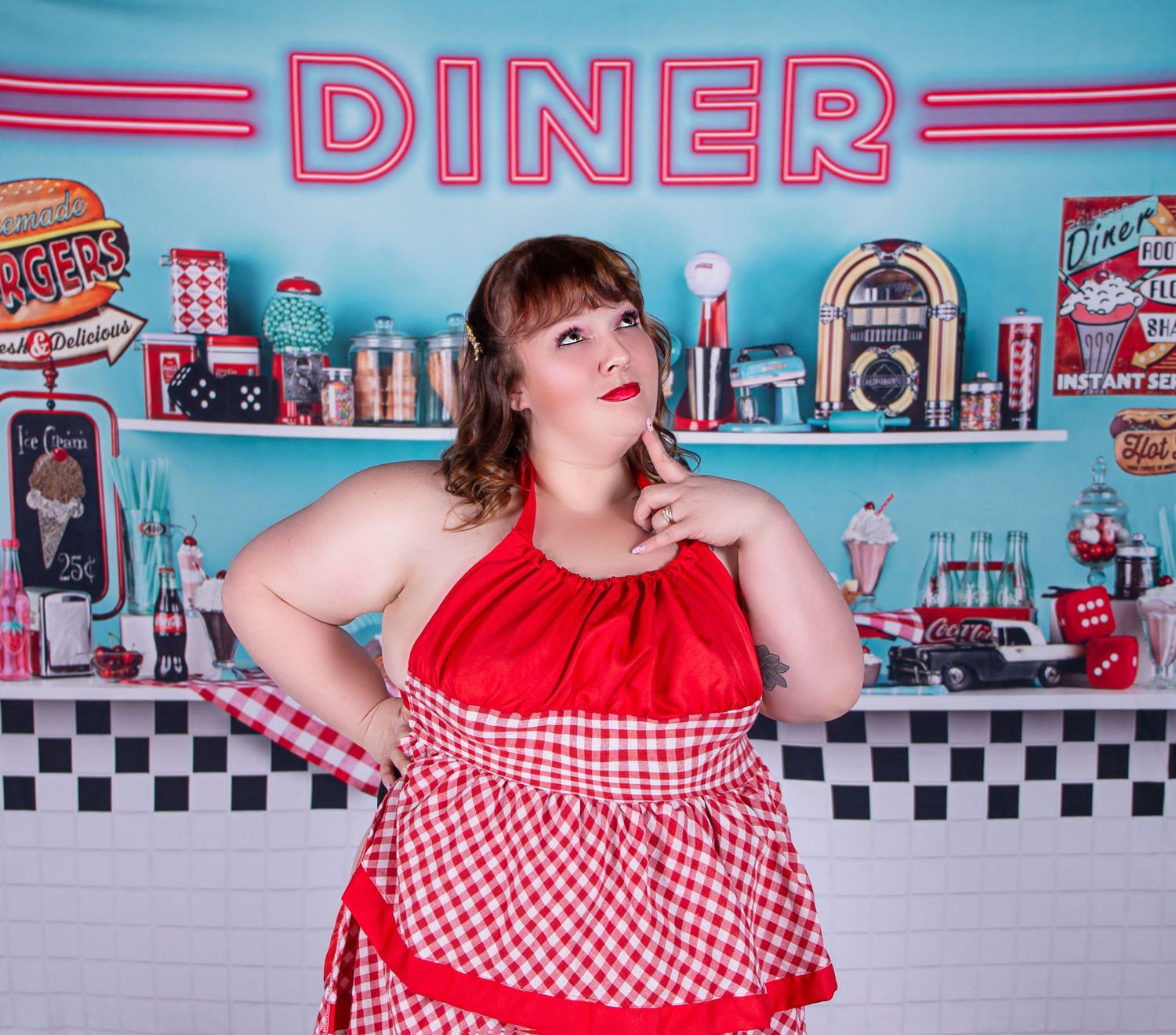 Retro 1950s diner interior with red and white checkered decor and neon signs on turquoise walls.