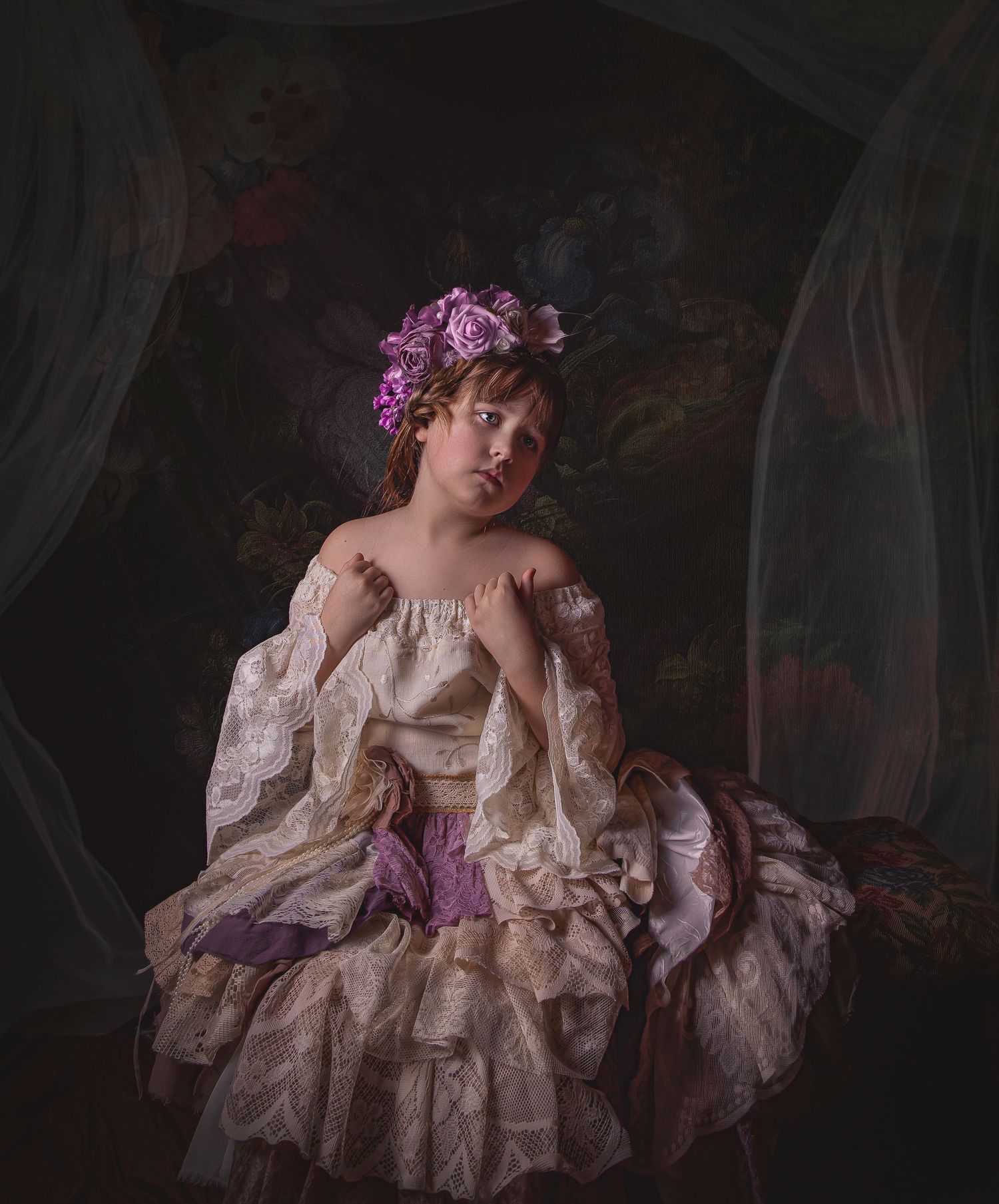 A figure in a vintage cream dress with purple flowers in their hair poses dramatically against a dark background.