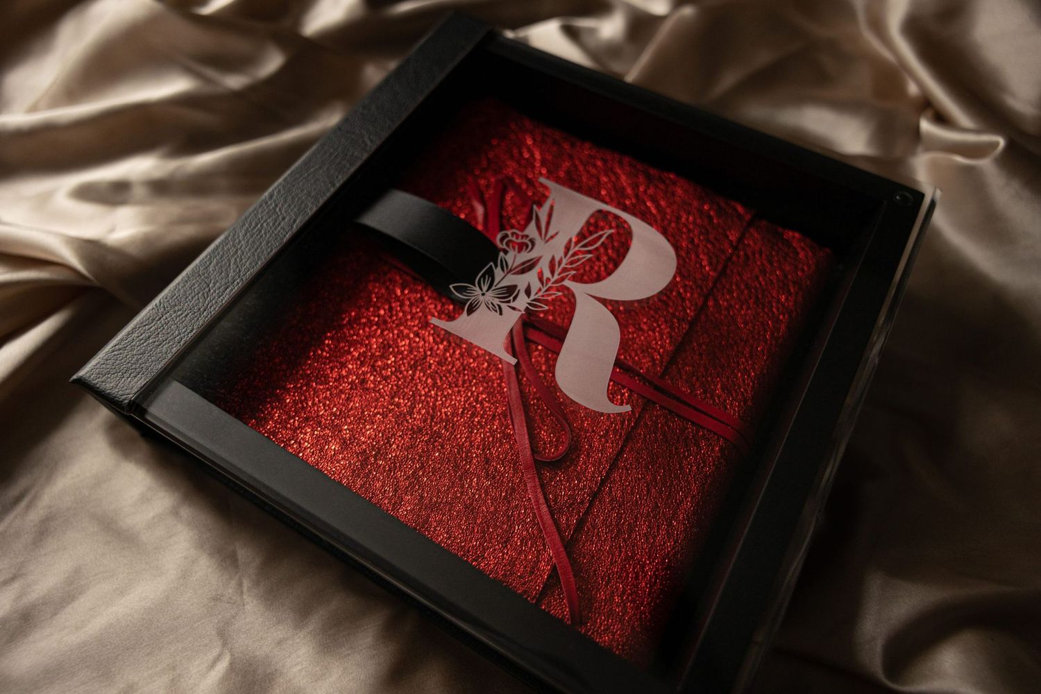 Wedding album with red detailing shown in progressive reveal shots on silk fabric.