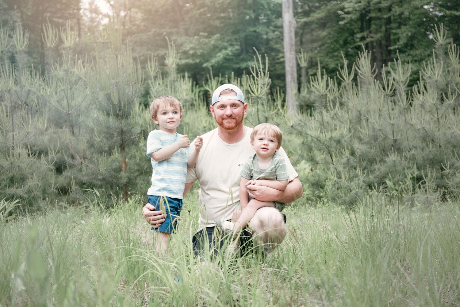 A casual outdoor family moment captured in soft, natural lighting among tall grass.