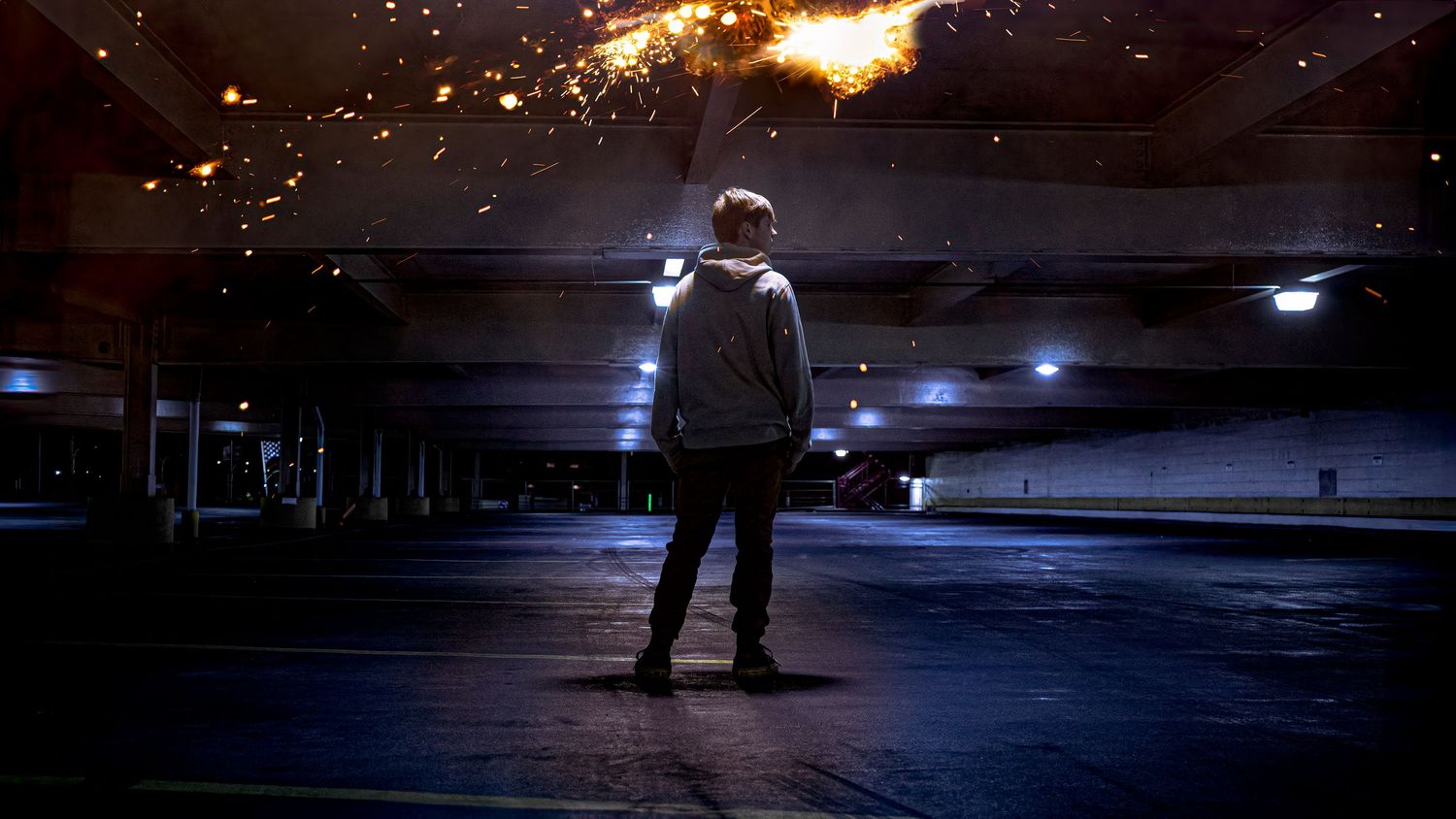 Silhouette of a person standing in an empty parking lot at night with dramatic lighting.