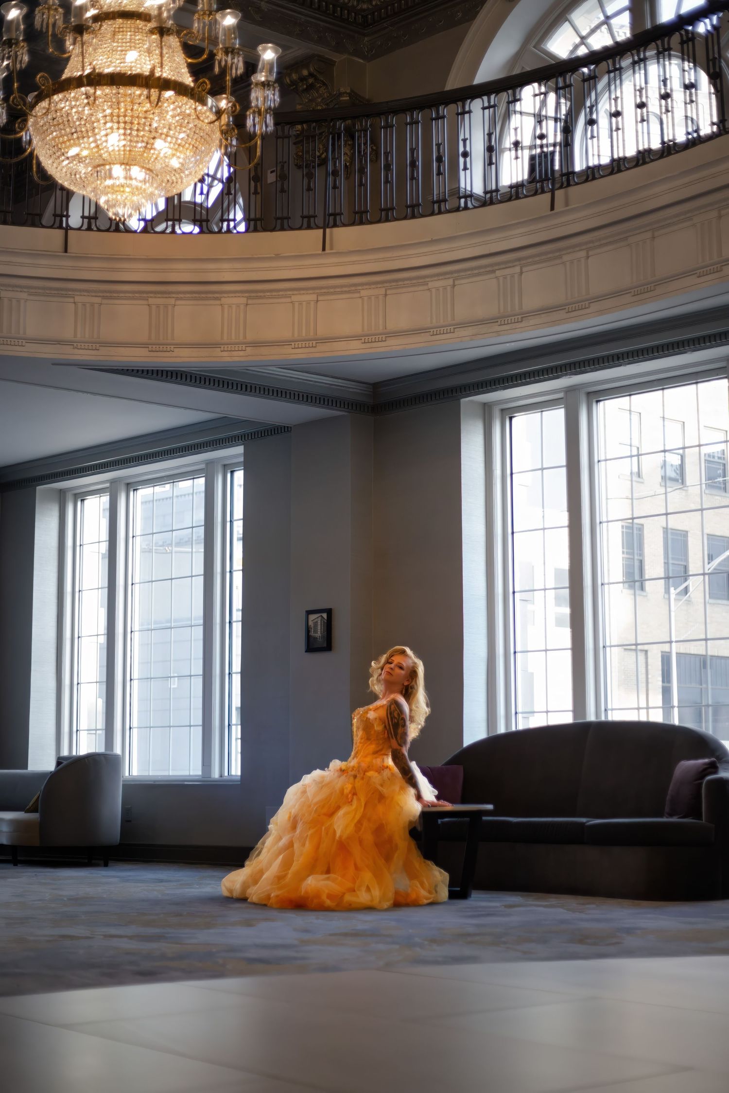 An elegant orange ballgown flows across an empty ballroom floor beneath crystal chandeliers.