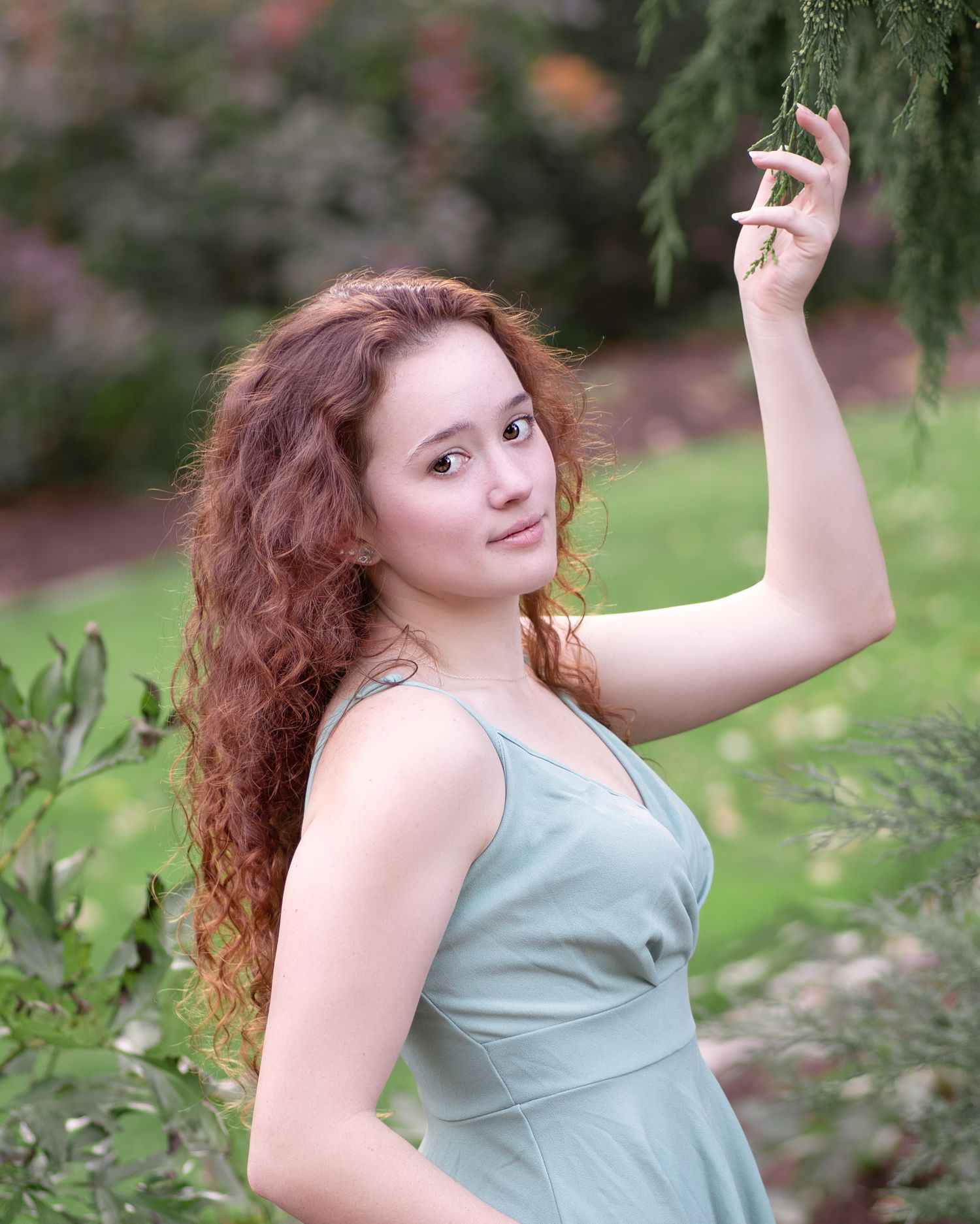 Portrait in a mint green dress among flowering garden plants.