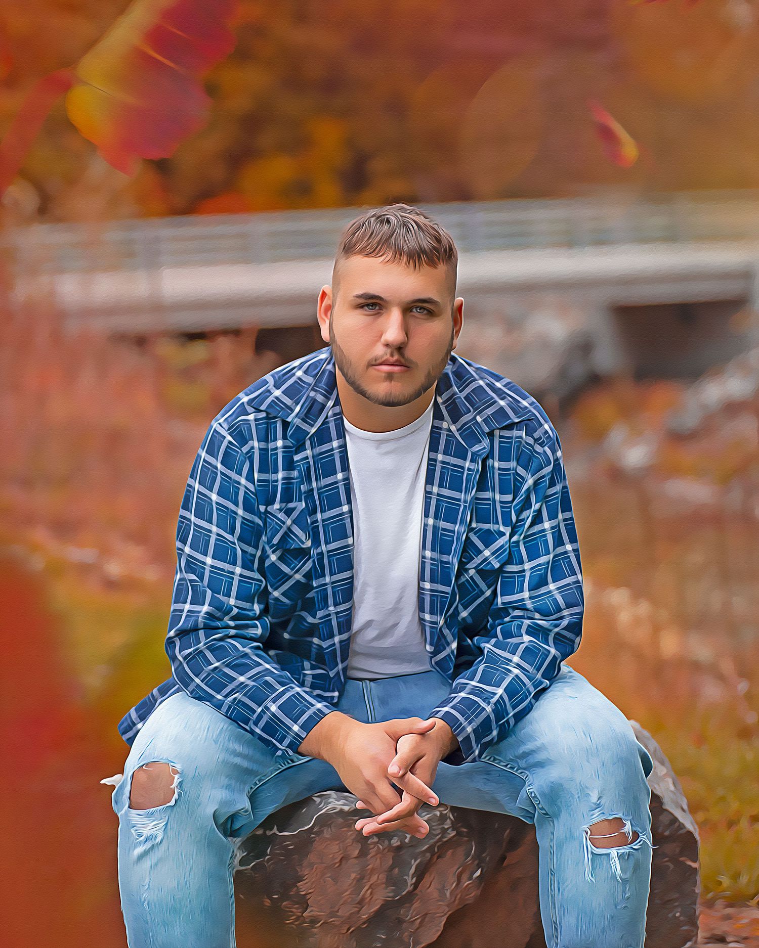 Fall portrait featuring someone in a plaid shirt and ripped jeans sitting on a rock.