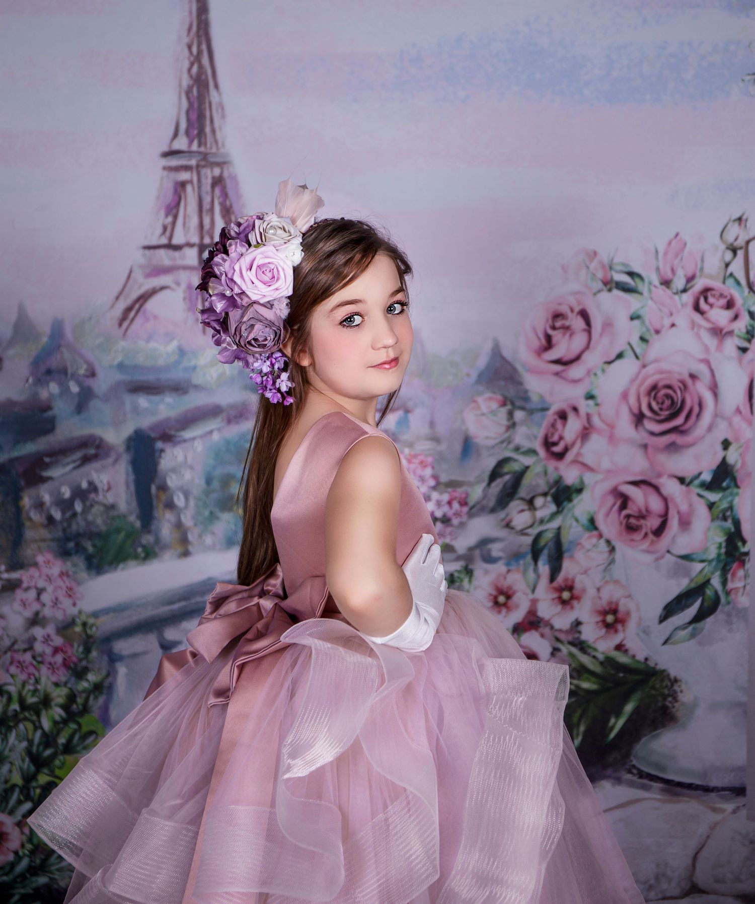 Romantic portrait in pink tulle gown against painted floral backdrop.