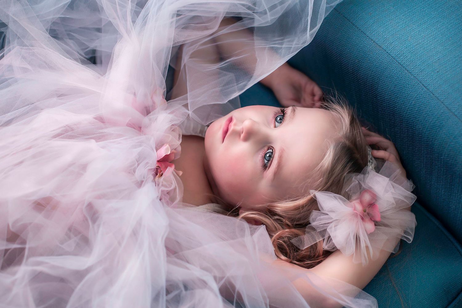 Dreamy portraits with soft pink tulle fabric against blue background.