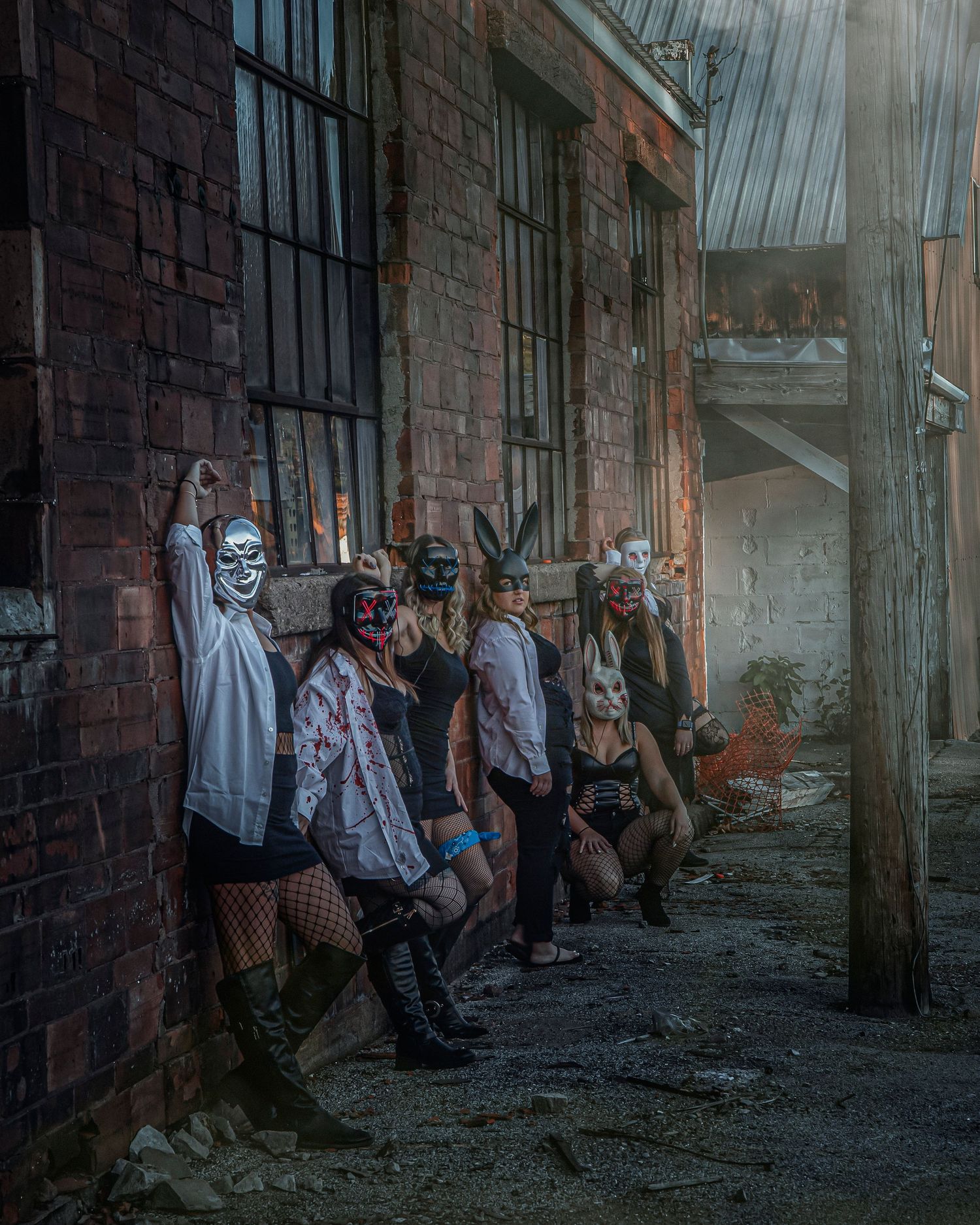 A group poses in a dark industrial hallway with dramatic lighting and shadows against brick walls.