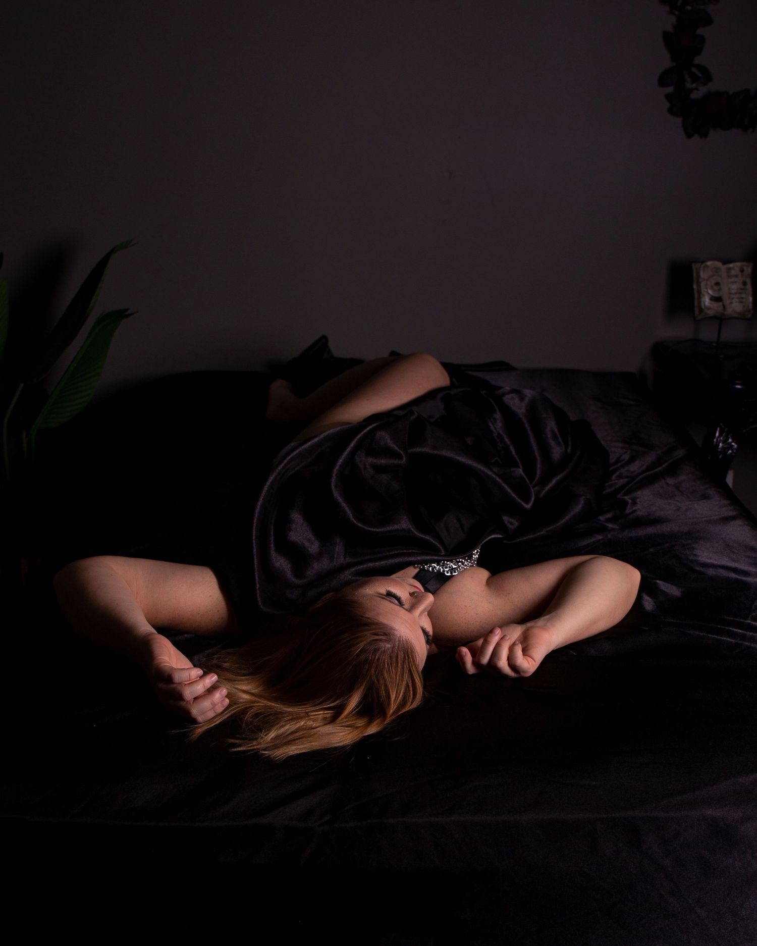 Moody black and white portrait series on dark bedding with dramatic shadows.