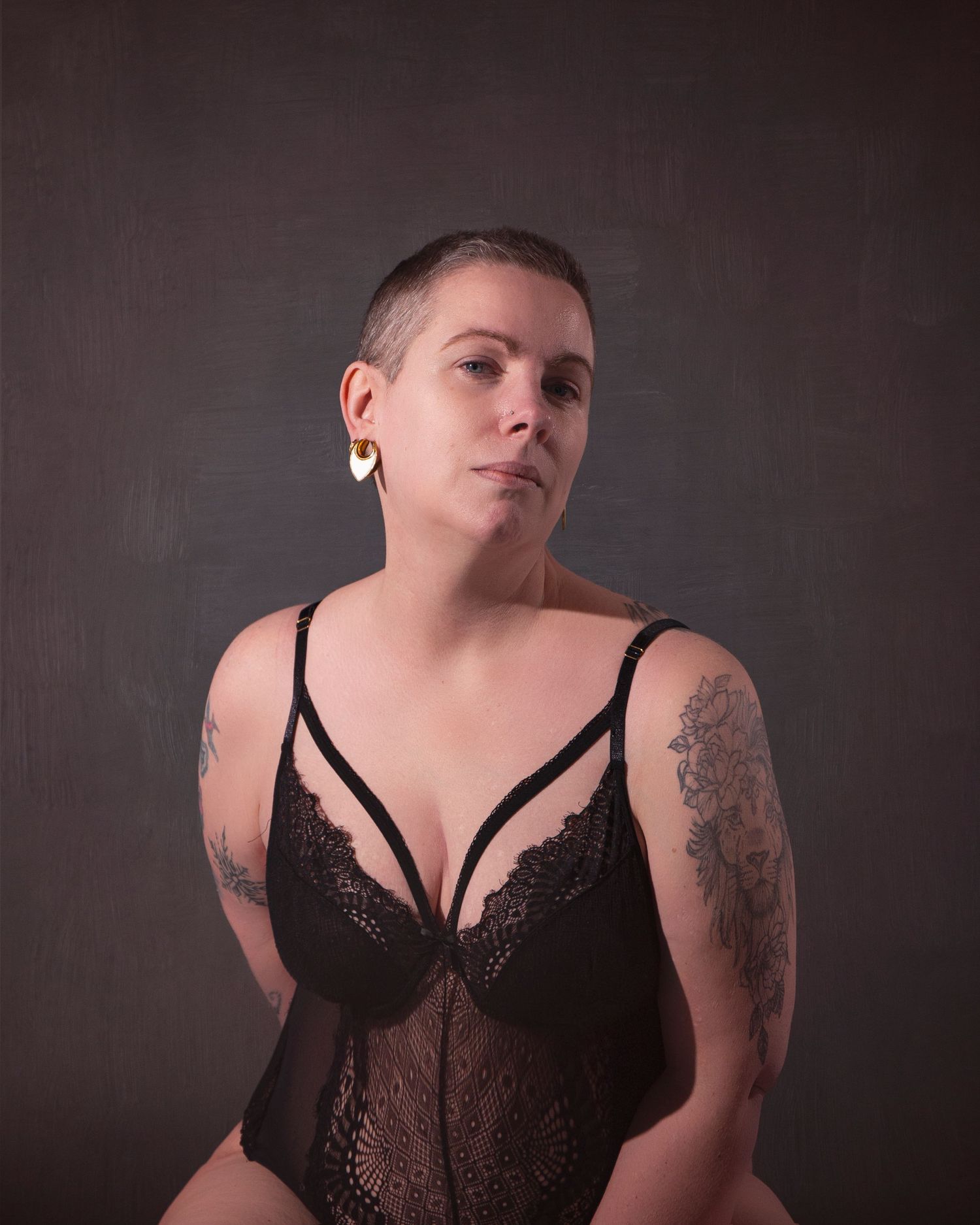Intimate portrait session featuring black lace lingerie against dark studio background.