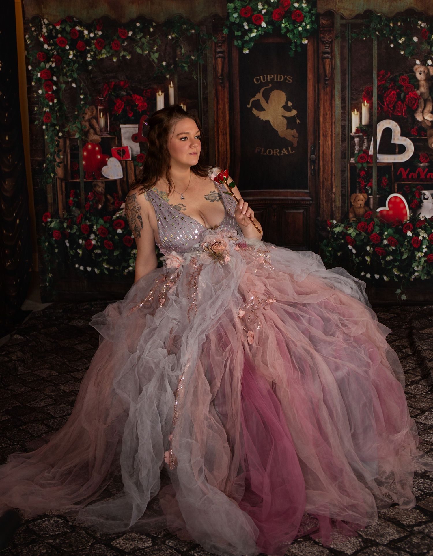 A romantic holiday scene with a flowing pink and gray tulle gown against a backdrop of twinkling lights and evergreen decor.
