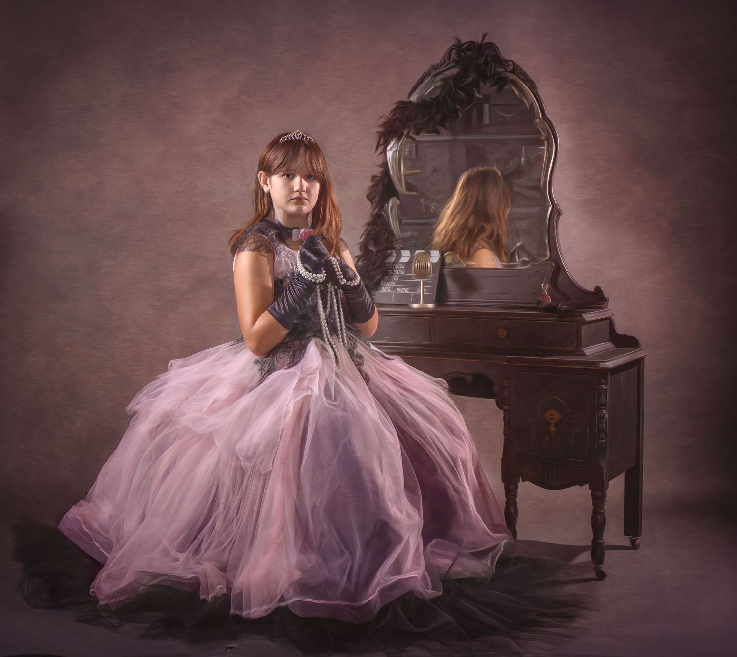 A figure in a flowing pink tulle gown sits at an ornate vintage vanity with a decorative mirror in a moody setting.