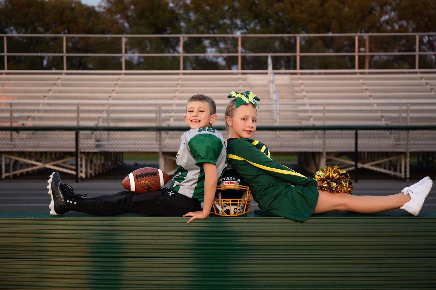 Athletes in green uniforms pose creatively on stadium bleachers with football gear.