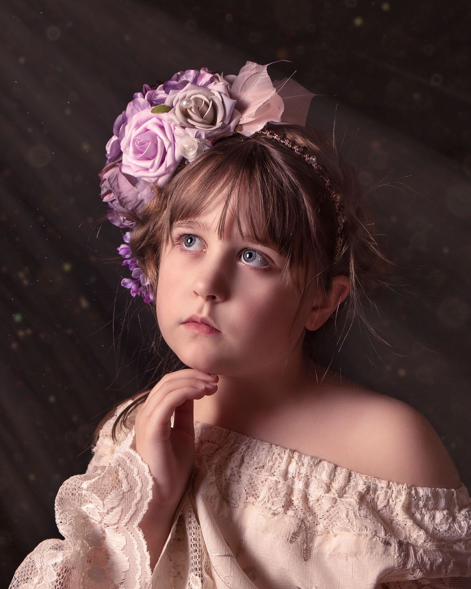 Artistic portrait with pink roses and lace dress against dark background in ethereal lighting.
