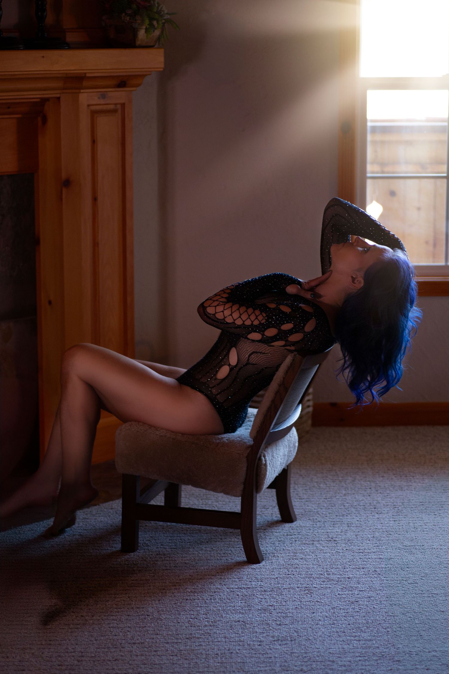 Artistic boudoir photography in dimly lit room with wooden accents.