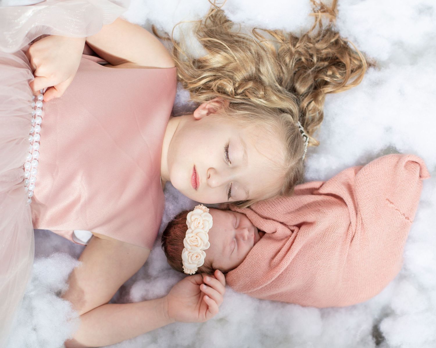 Ethereal portrait photography on white fabric with soft pink tones and delicate styling.