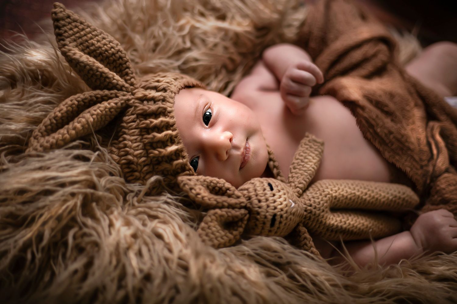 Artistic portrait series with soft brown tones and textured blanket backdrop.
