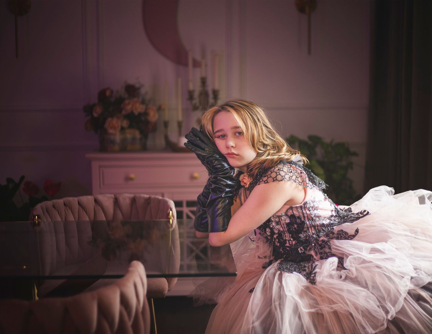 A dreamy portrait of a woman in a tulle dress sitting on a vintage sofa in a pink-toned room.