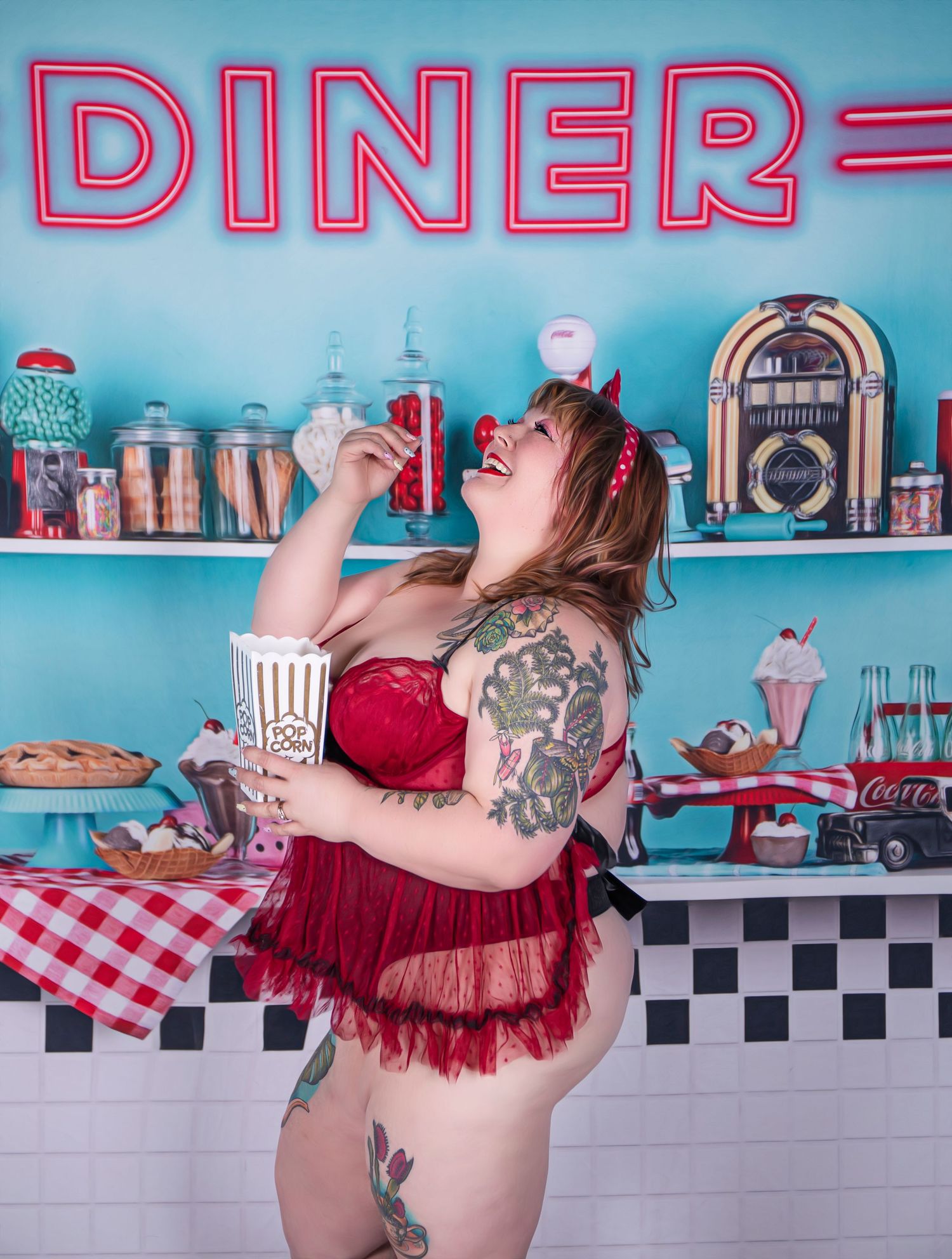A person in a red dress poses playfully in a retro-style diner setting with checkered floors and turquoise walls.