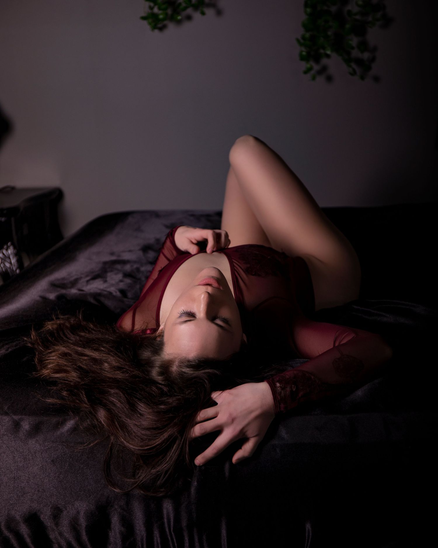 A series of moody boudoir photos showing a woman in dark lighting laying on a bed.