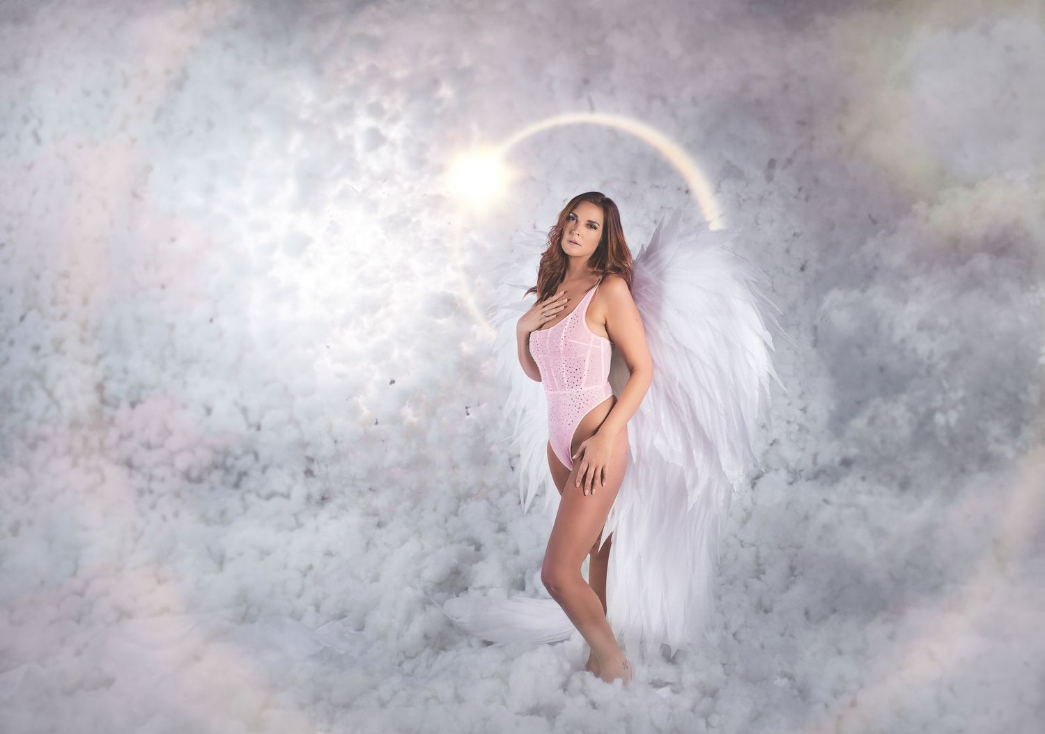 A figure in white fabric poses gracefully against a misty gray studio backdrop creating an ethereal artistic effect.