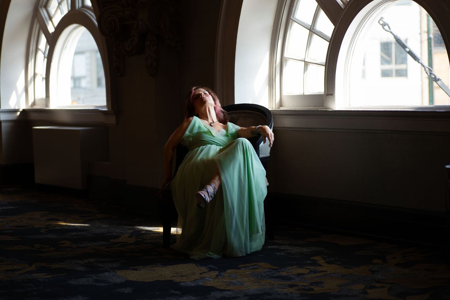Sunlit interior of an elegant room with arched windows and classical architectural details.