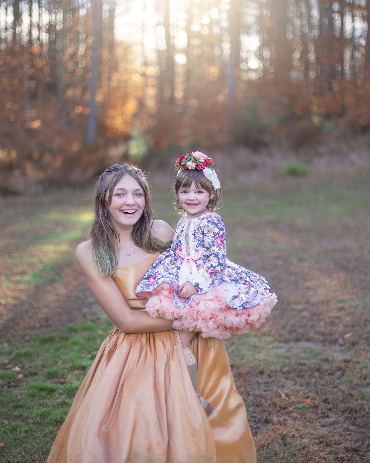 Outdoor autumn photoshoot with gold dress in sunlit forest setting.