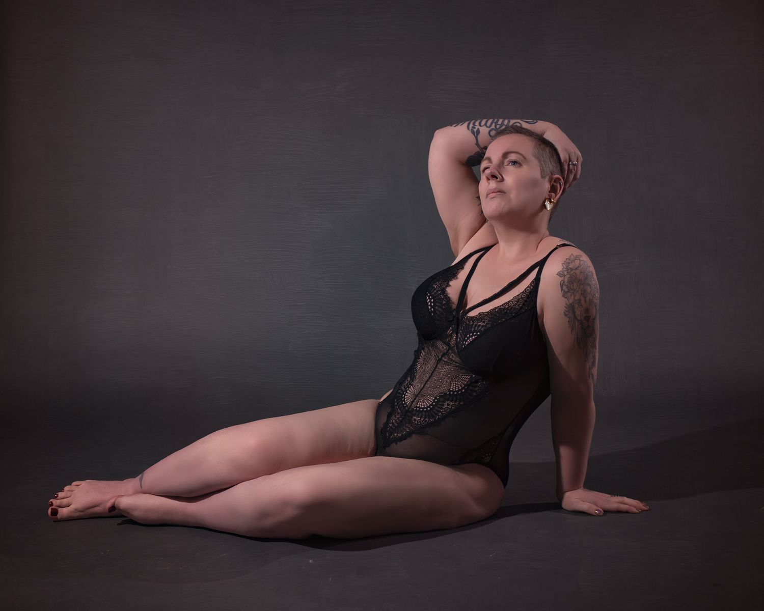 Dramatic boudoir photography with moody lighting and dark background.