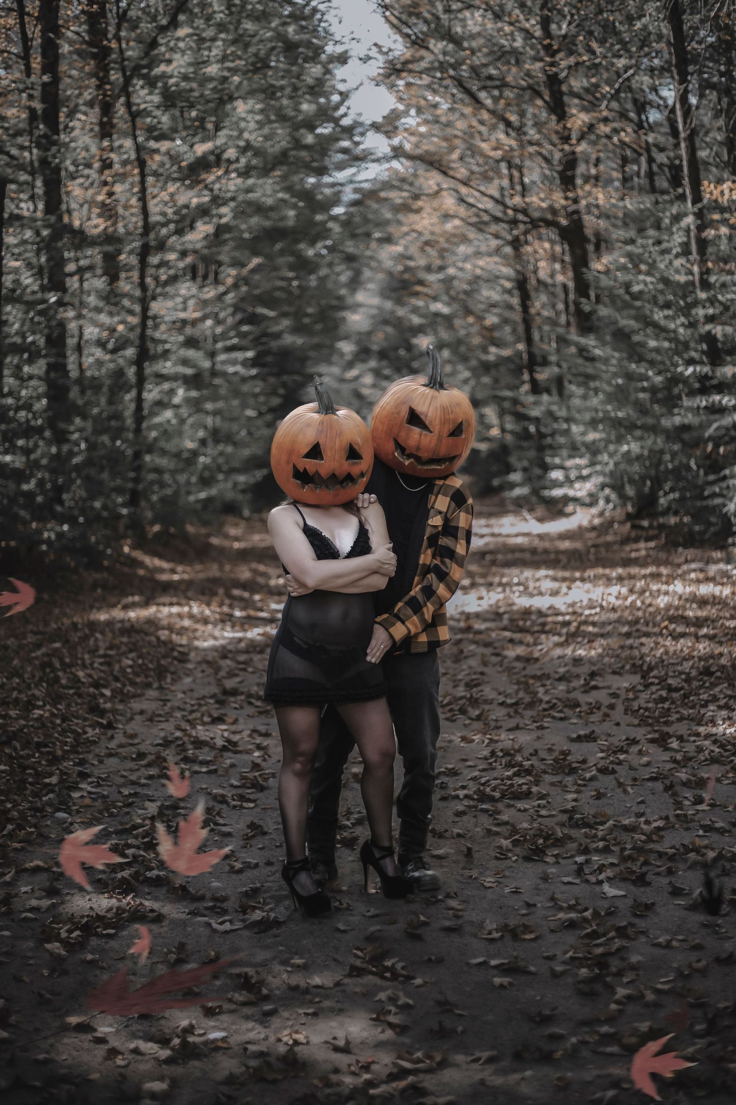 Creative autumn photography with pumpkin heads and falling leaves in moody forest setting.