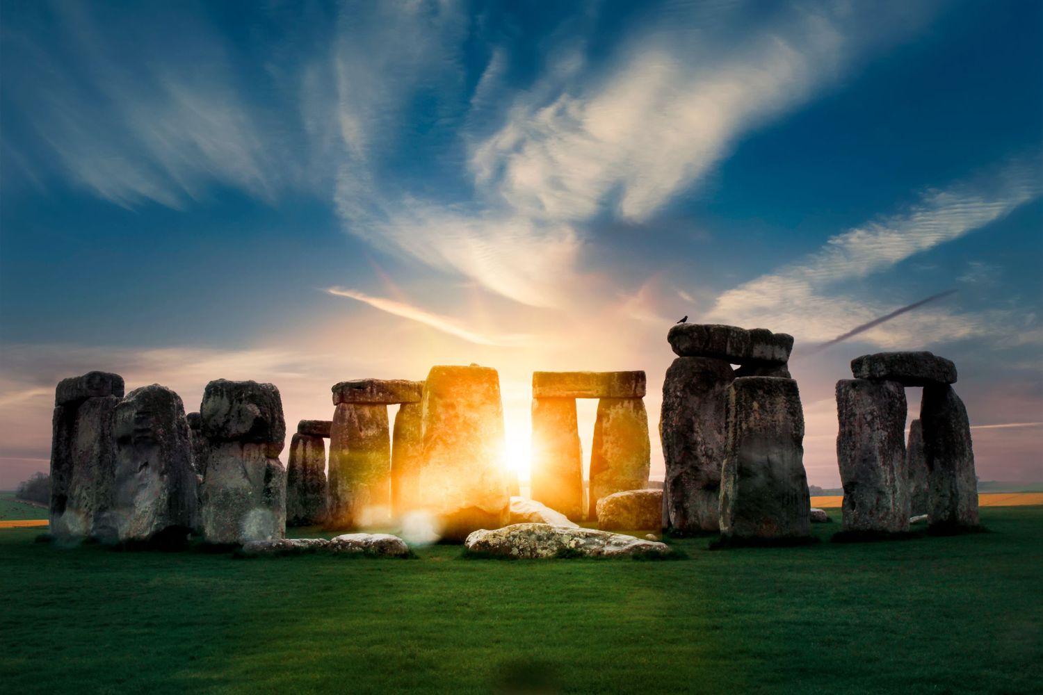 Dramatic sunset silhouettes the ancient stone circle of Stonehenge against a vibrant blue and orange sky.