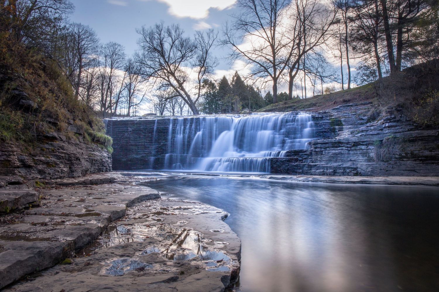 Panoramic waterfall views with rocky shores and flowing water in natural forest setting.