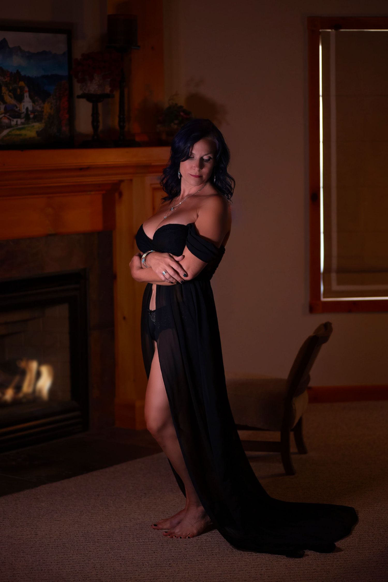 Intimate indoor boudoir session with warm lighting and wooden furniture.