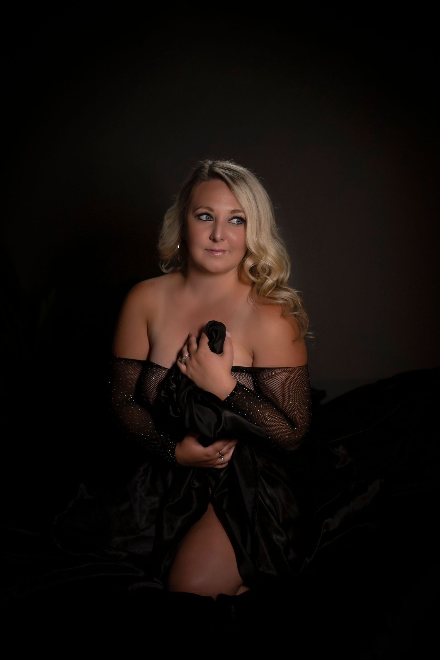 Moody boudoir photography session with dark dramatic lighting.