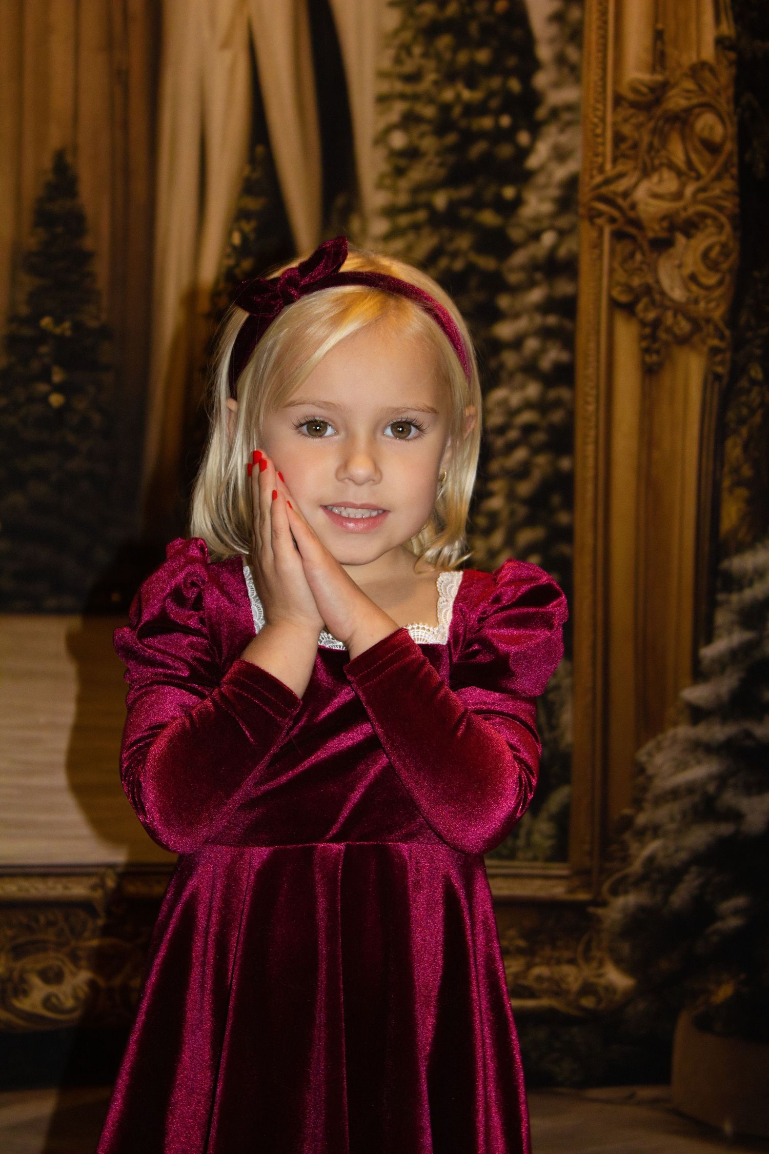 Elegant holiday portrait setup with burgundy velvet and ornate Christmas decorations.