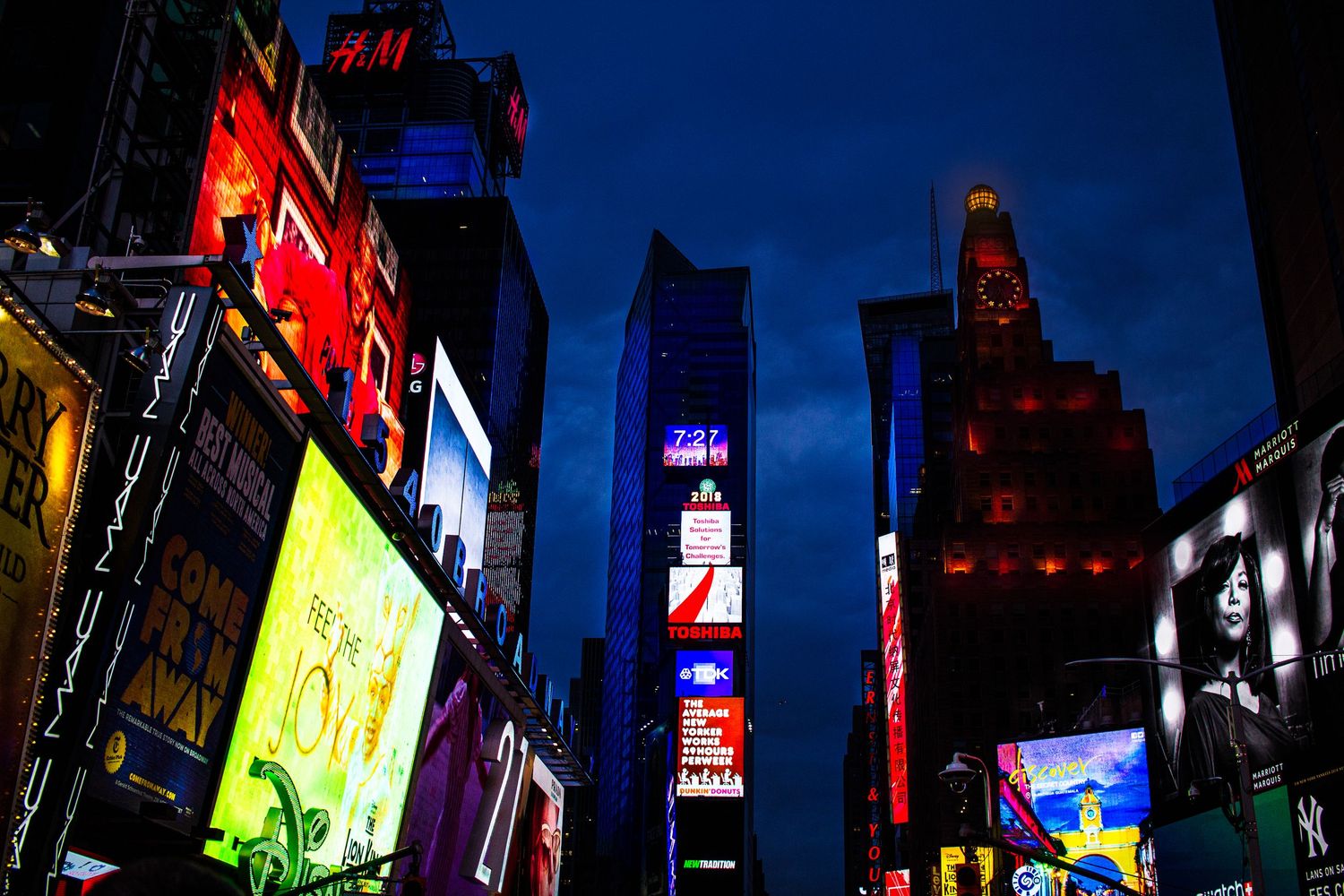 Vibrant neon signs and digital billboards illuminate Times Square in New York City at night.