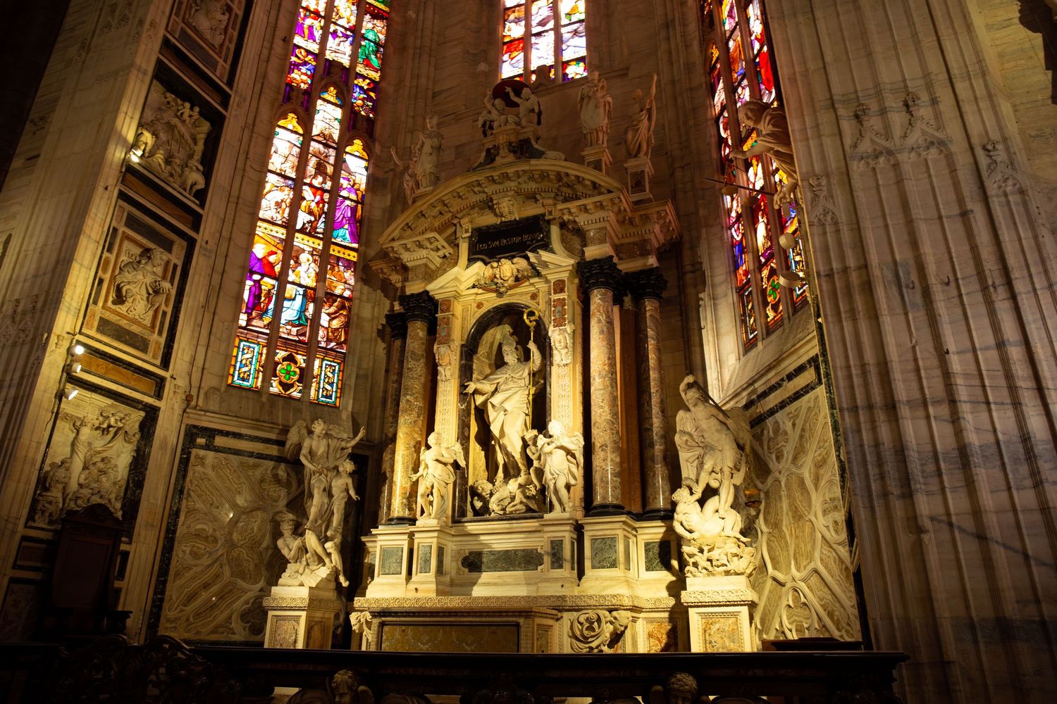 Ornate Gothic cathedral interior with soaring stone columns, stained glass windows, and dramatic religious sculptures.