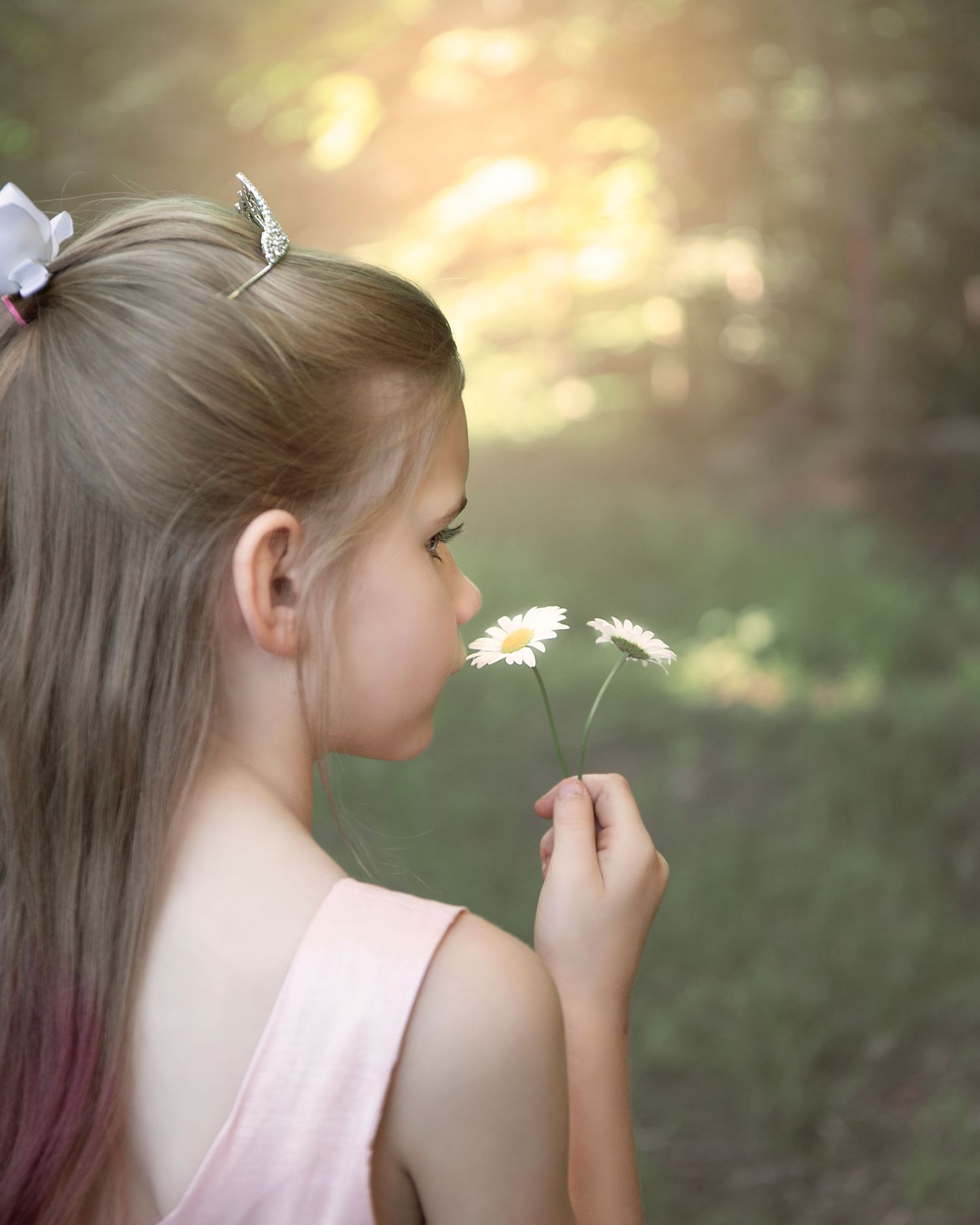 Delicate outdoor portrait with a dandelion flower in soft natural lighting.