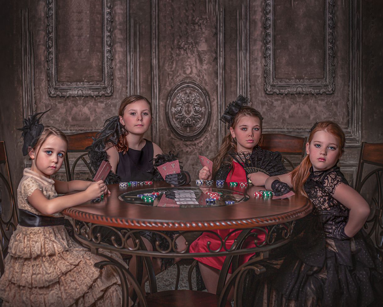 Historical themed photoshoot with antique table setting and period costumes in dramatic lighting.