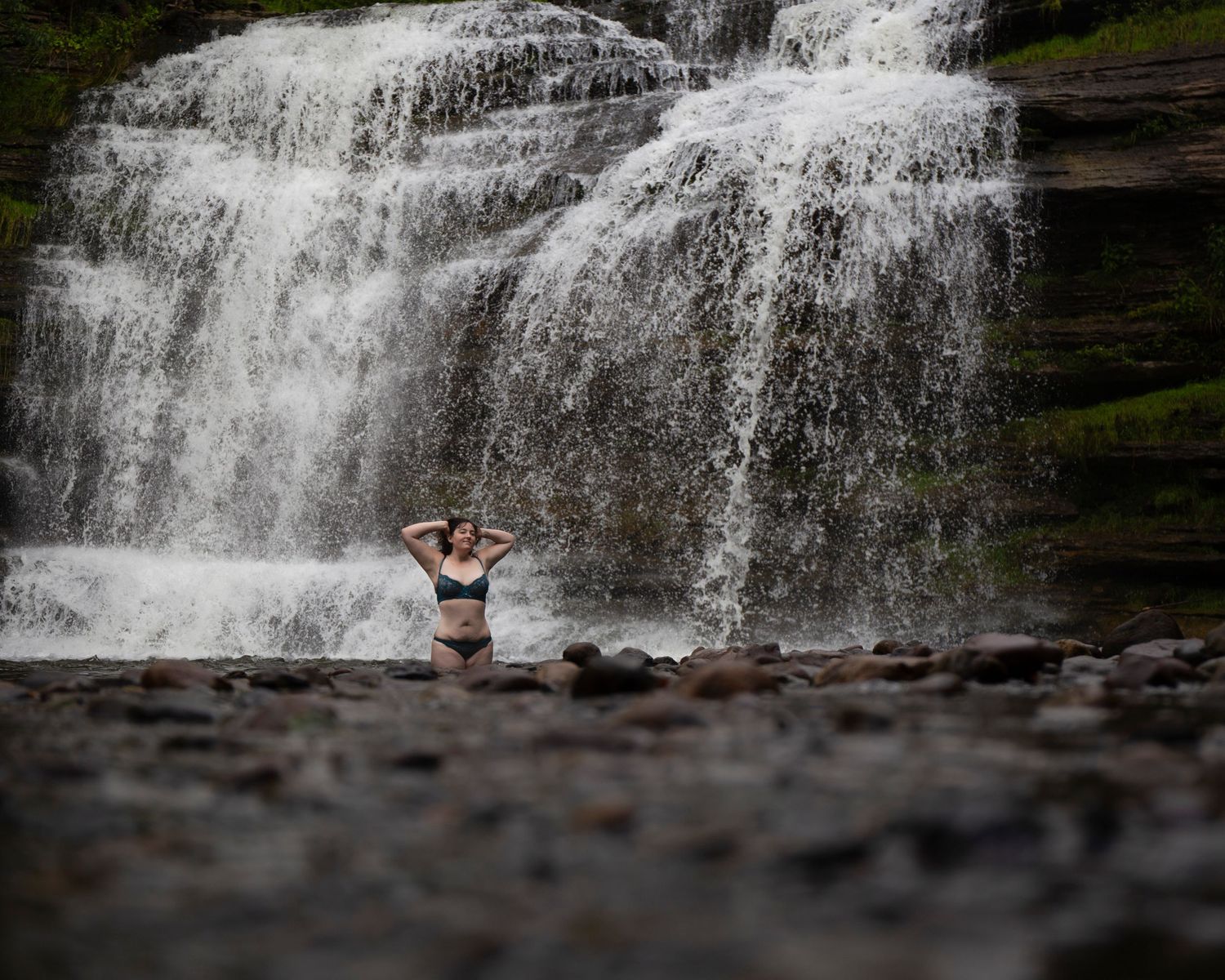 A series of eight sequential waterfall photos showing someone gradually emerging from behind the cascading water.